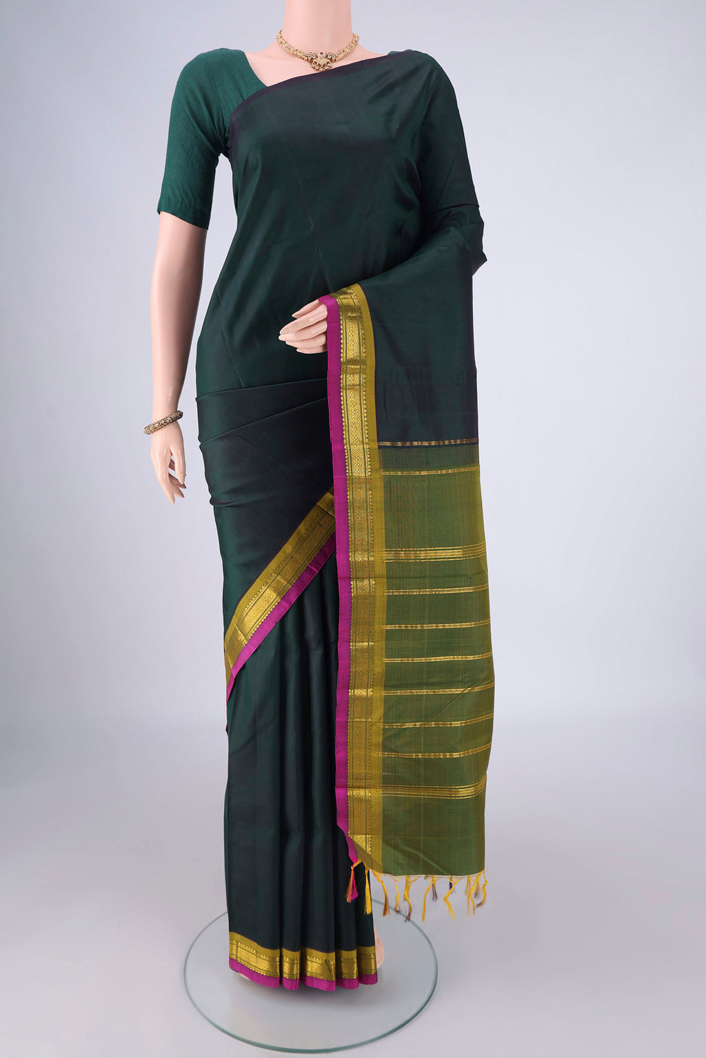 Bottle Green Kanjivaram Silk Saree with Plain Body and One Side Border.  displayed on a mannequin