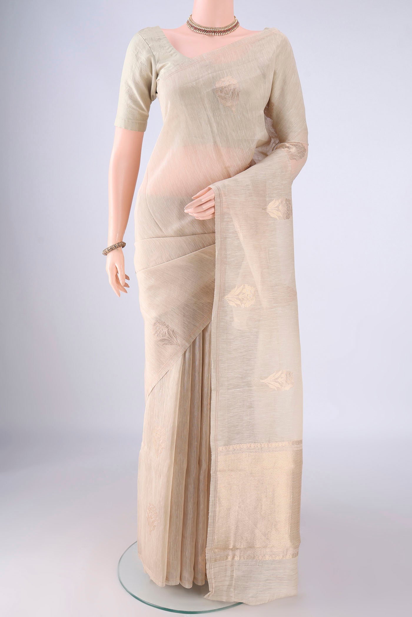 Beige Linen Saree with Zari Butta on the body and Thin Zari Line.  displayed on a mannequin