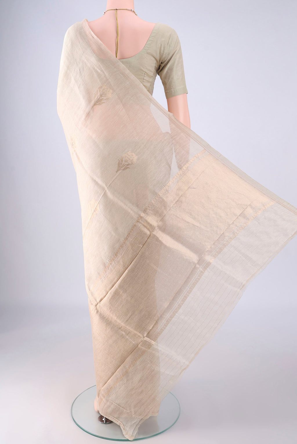 Flat view of Beige Linen Saree with Zari Butta on the body and Thin Zari Line. 