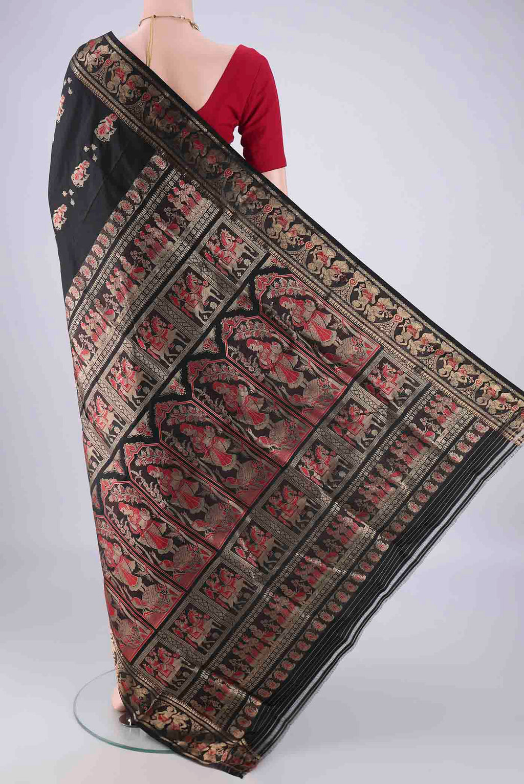 Flat view of Black Baluchari Silk Saree with Zari And Thread Butta on the body and Zari Border. 