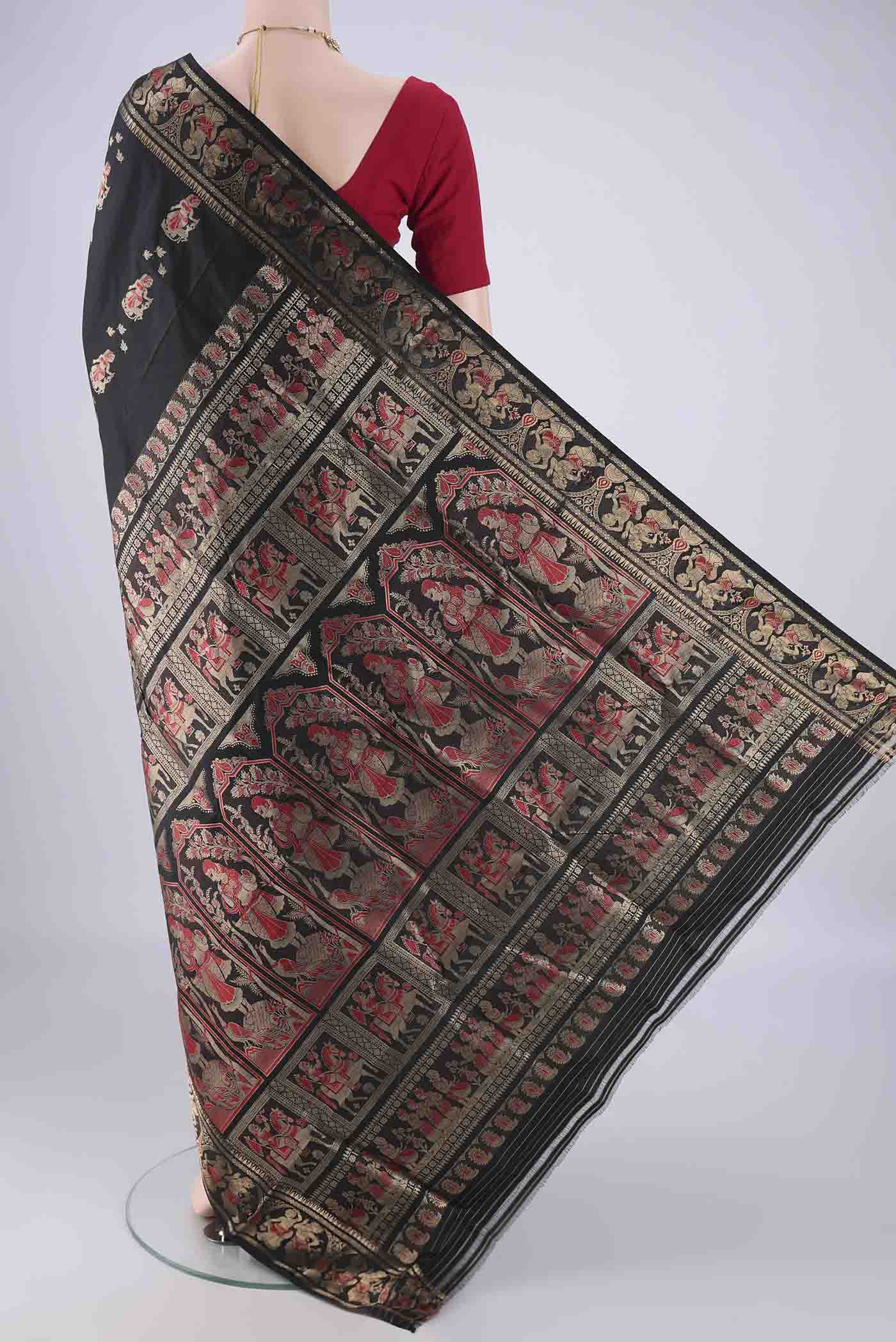 Flat view of Black Baluchari Silk Saree with Zari And Thread Butta on the body and Zari Border. 
