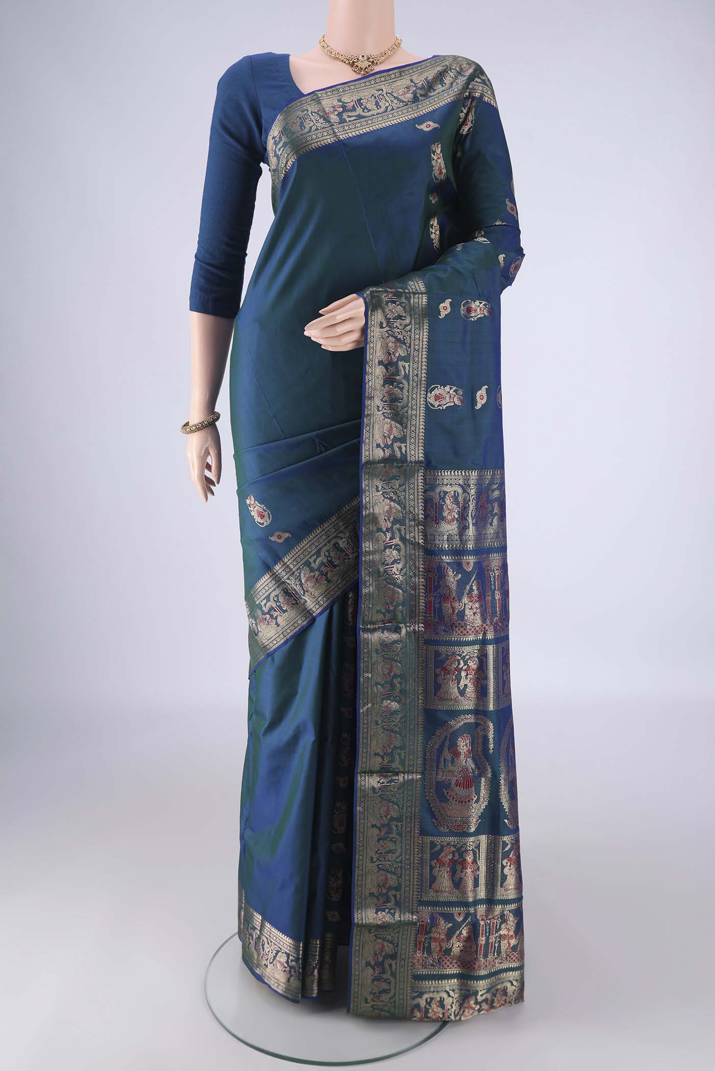 Peacock Blue Baluchari Silk Saree with Zari And Thread Butta on the body and Zari Border.  displayed on a mannequin