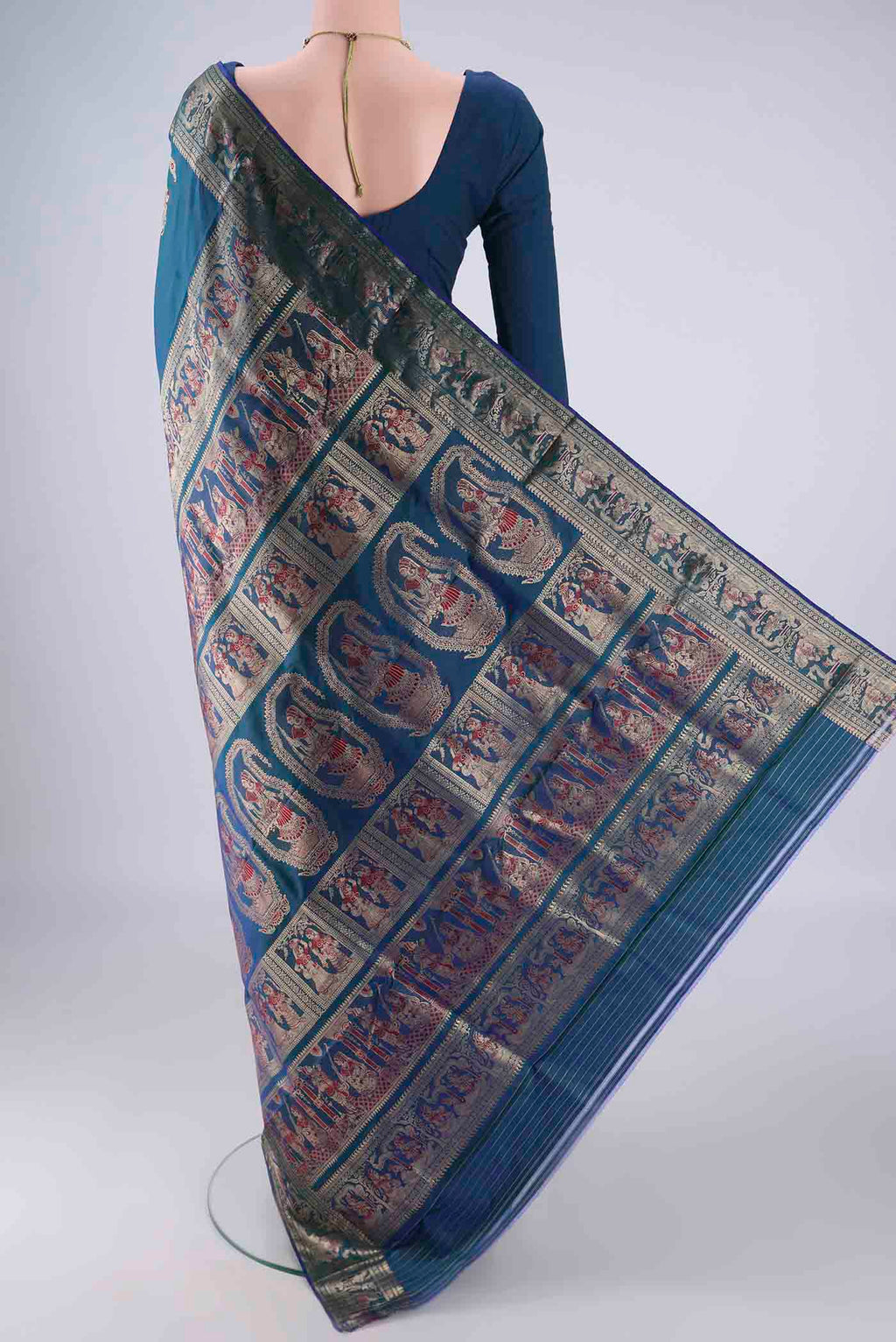 Flat view of Peacock Blue Baluchari Silk Saree with Zari And Thread Butta on the body and Zari Border. 