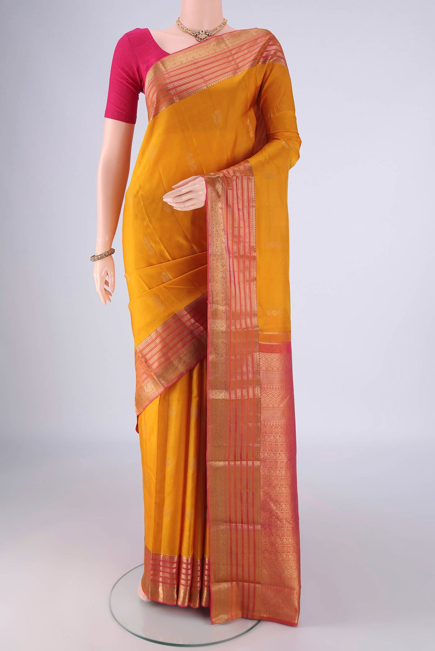 Yellow Kanchipuram Silk Saree with Zari Butta on the body and Zari Border.  displayed on a mannequin