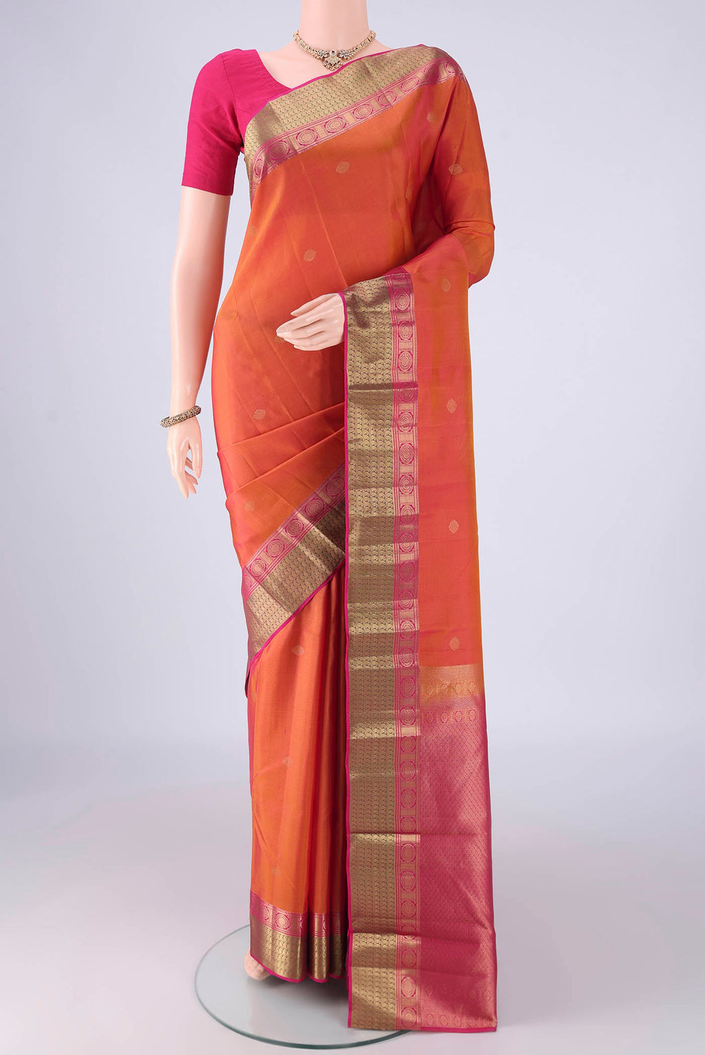 Brick Orange Kanchipuram Silk Saree with Zari Butta on the body and Zari Border.  displayed on a mannequin