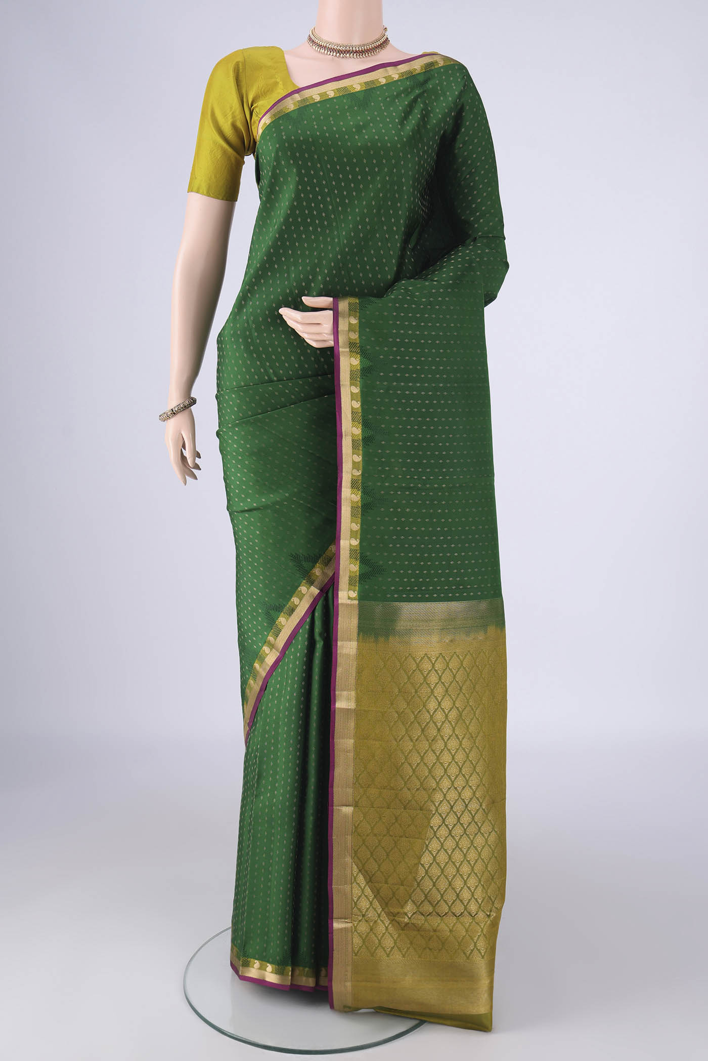 Bottle Green Kanchipuram Silk Saree with Zari Butta on the body and Zari Border.  displayed on a mannequin