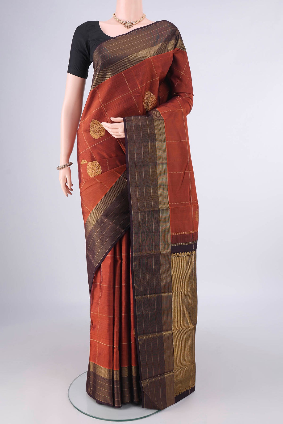 Pure Silk Rust Kanjivaram Saree with Checked design on the body and Zari Border.  displayed on a mannequin