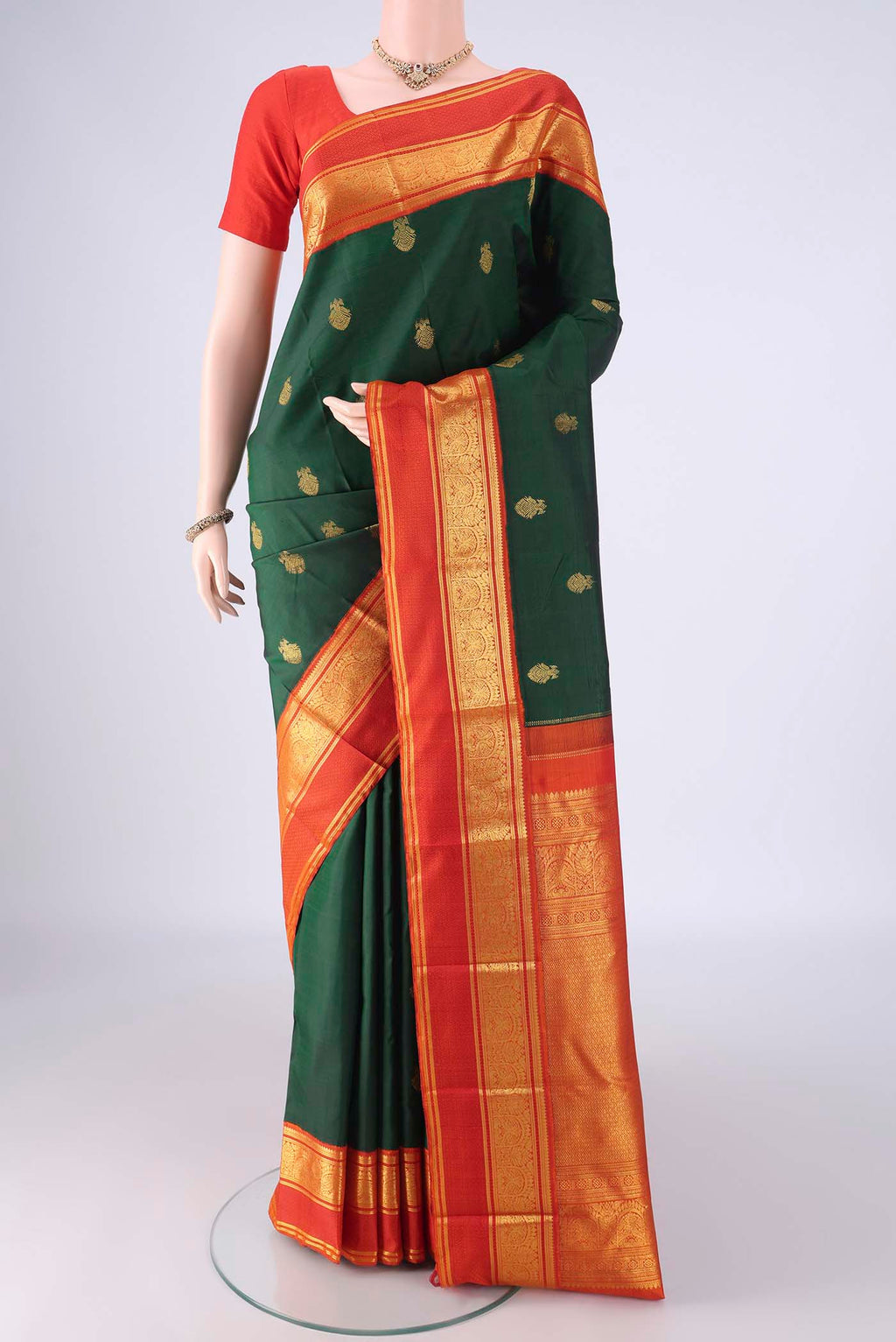 Bottle Green Kanchipuram Silk Saree with Zari Butta on the body and Zari Border.  displayed on a mannequin