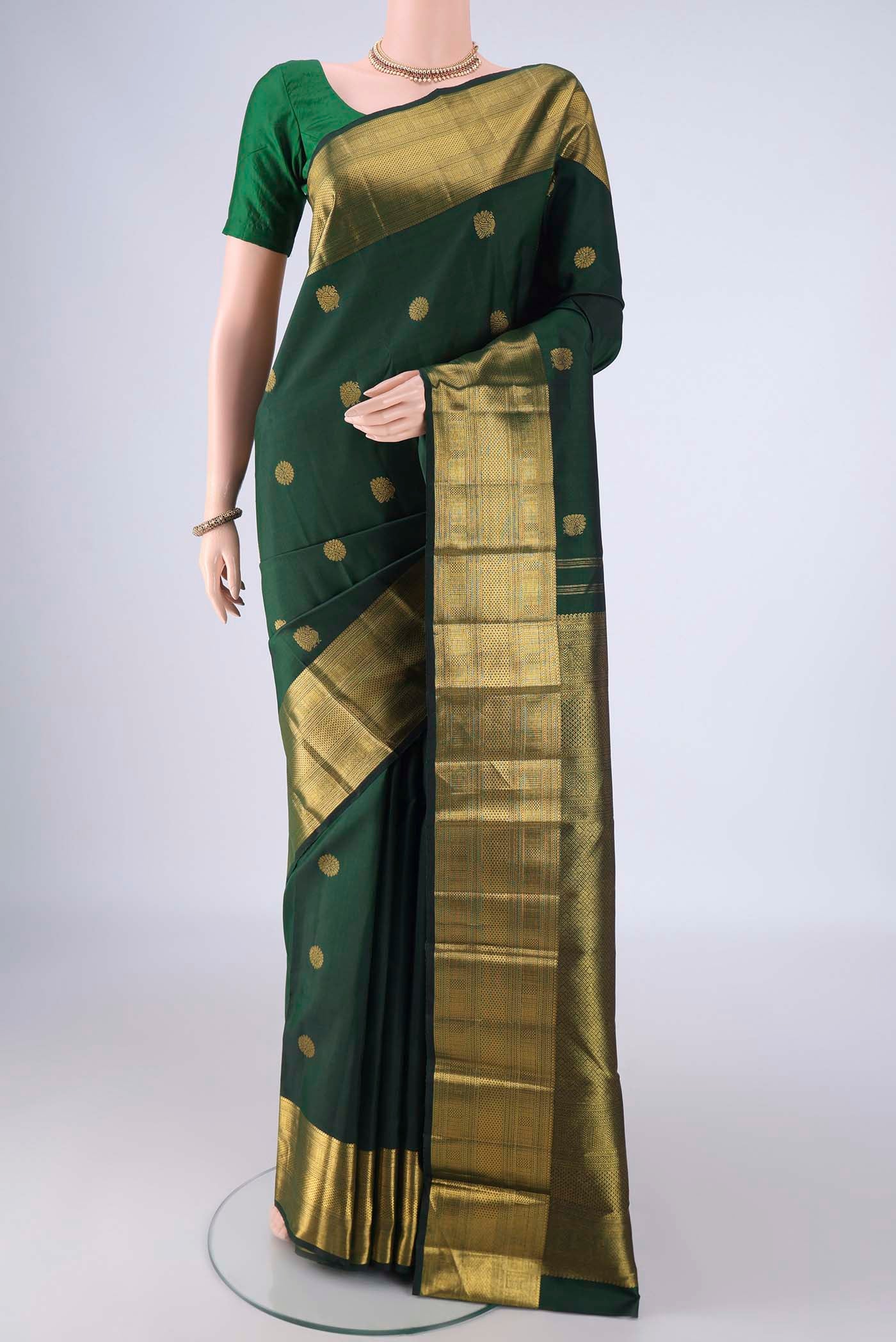 Bottle Green Kanjivaram Silk Saree with Zari Butta on the body and Zari Border.  displayed on a mannequin
