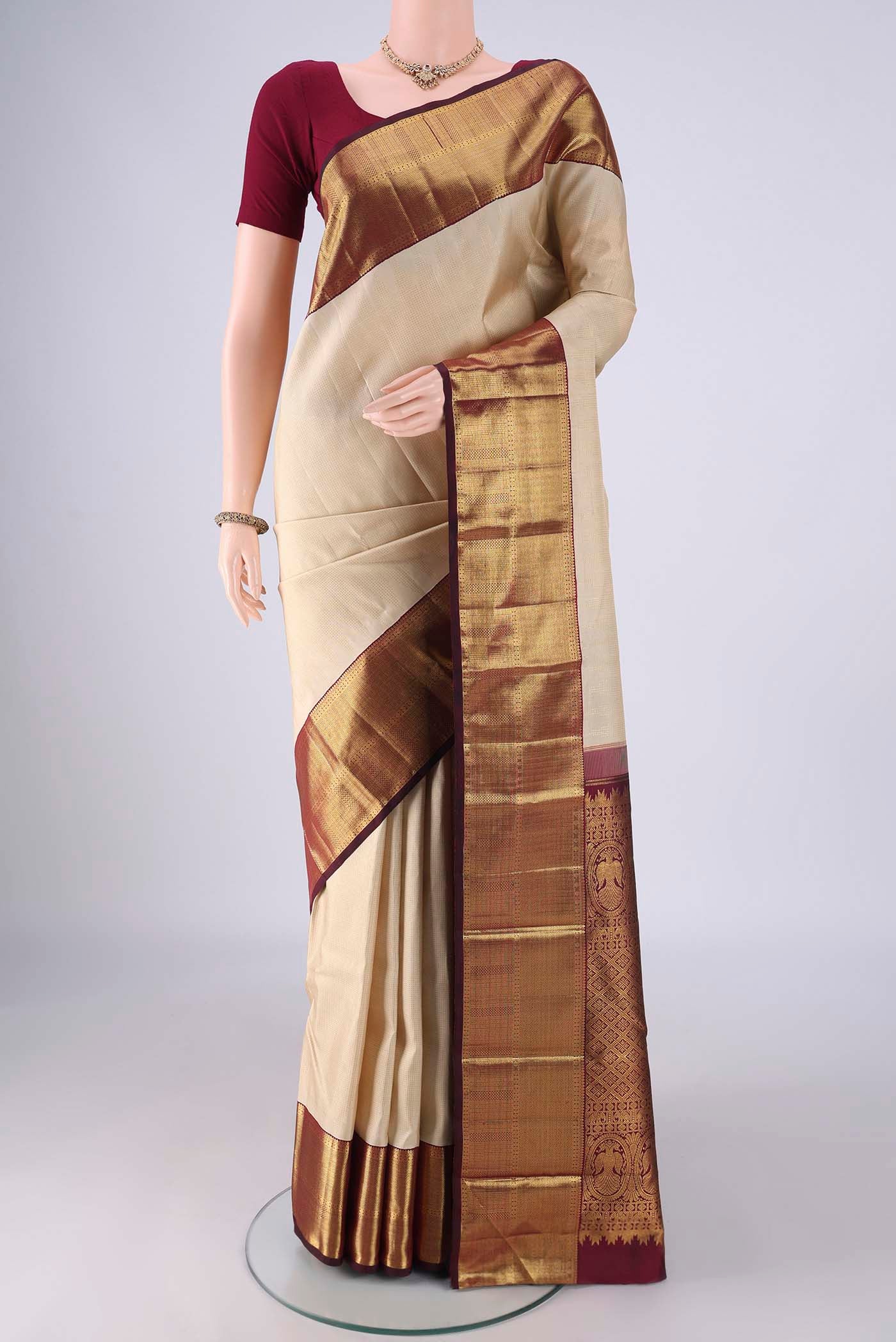 Cream Kanchipuram Silk Saree with Stripes on the body and Temple Border.  displayed on a mannequin