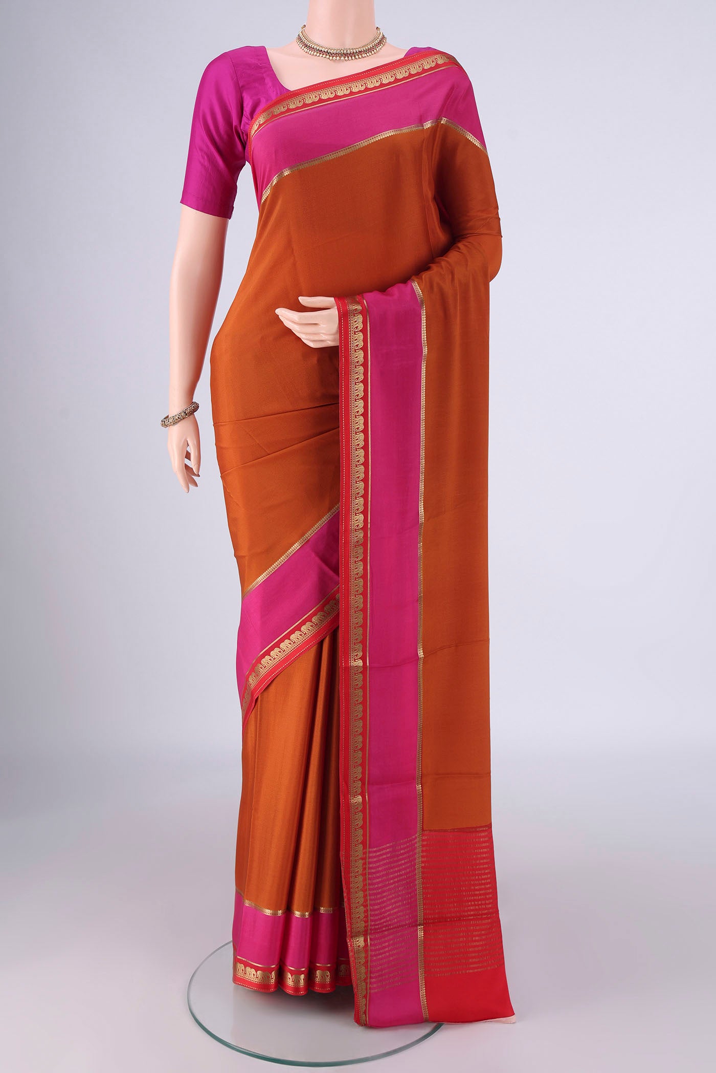 Rust Mysore Crepe Saree with Plain Body and Zari Border.  displayed on a mannequin
