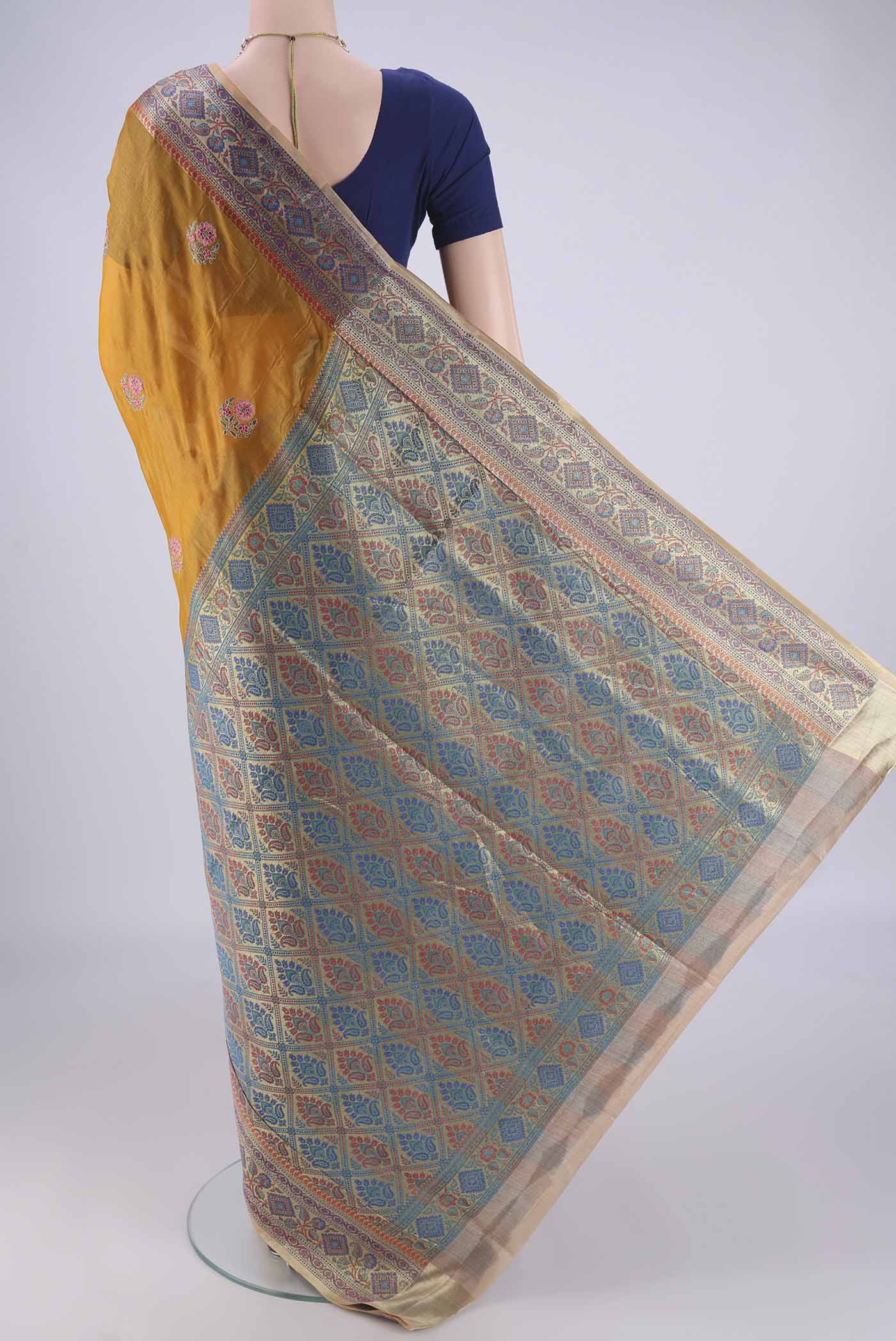 Flat view of Mustard Banarasi Tussar Silk Saree with Embroidery on the body and Zari Border. 