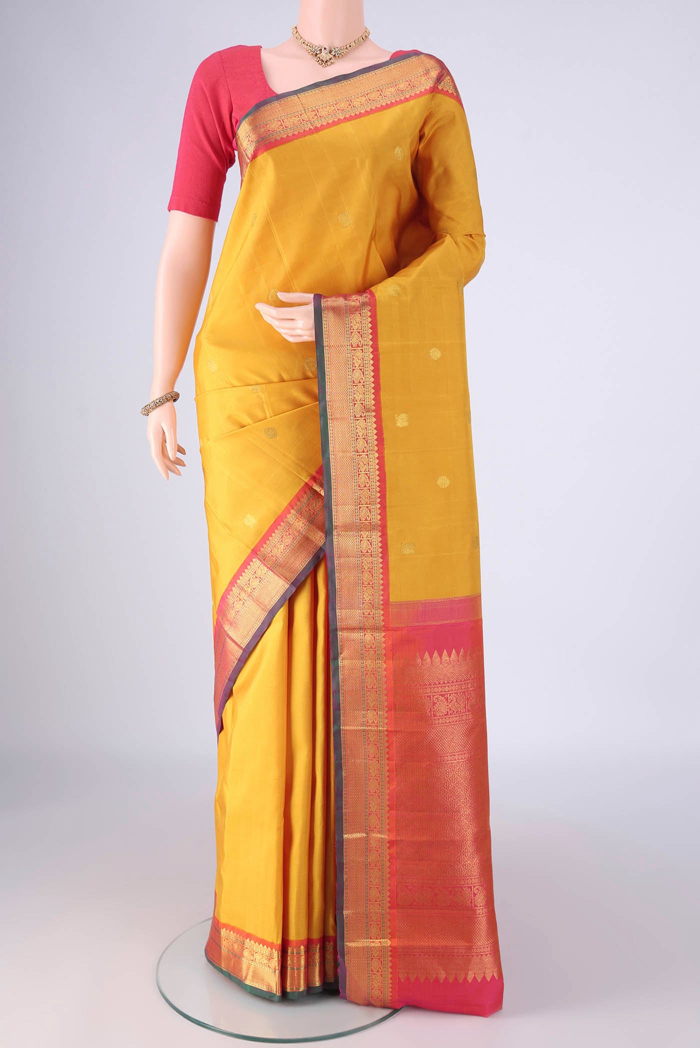 Yellow Kanjivaram Silk Saree with Zari Butta on the body and Zari Border.  displayed on a mannequin