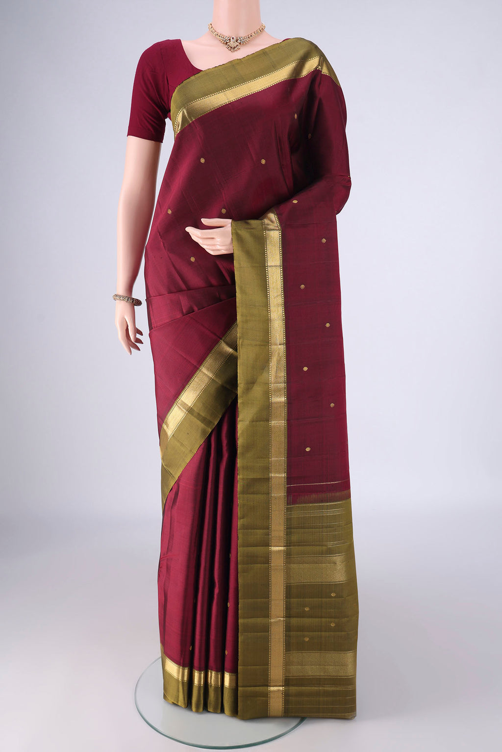 Maroon Kanchipuram Silk Saree with Zari Butta on the body and Zari Border.  displayed on a mannequin