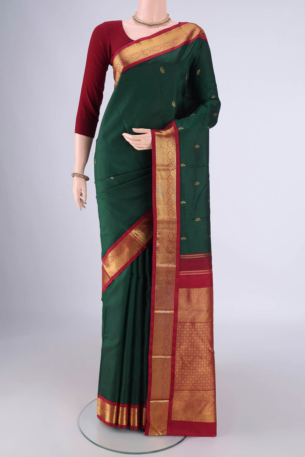 Bottle Green Kanchipuram Silk Saree with Zari Butta on the body and Zari Border.  displayed on a mannequin