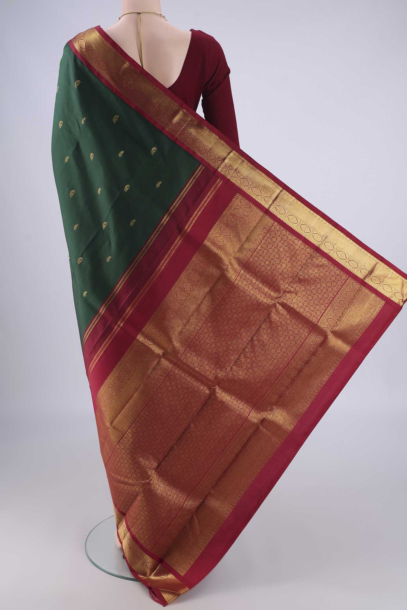 Flat view of Bottle Green Kanchipuram Silk Saree with Zari Butta on the body and Zari Border. 