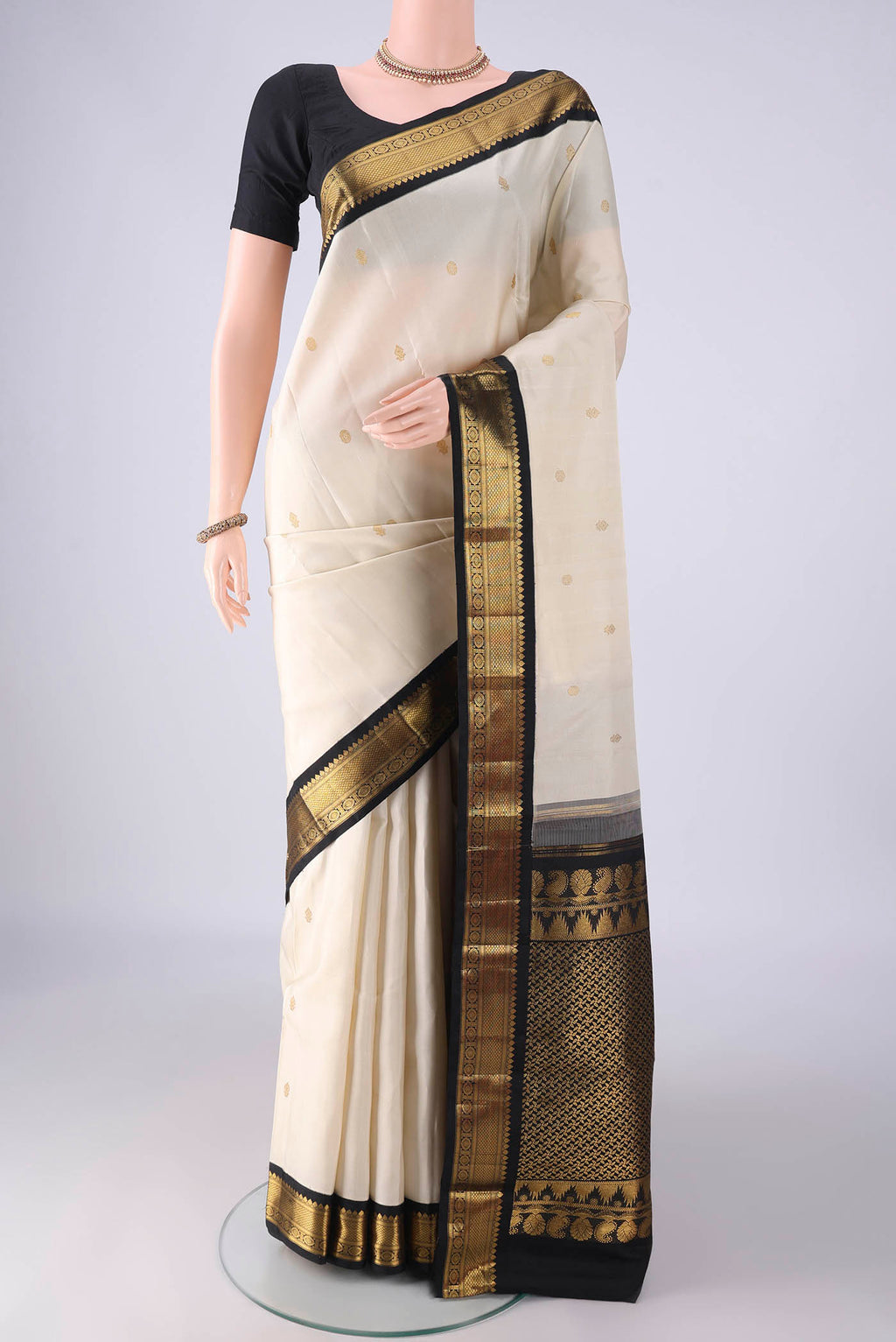 Off White Kanchipuram Silk Saree with Zari Butta on the body and Zari Border.  displayed on a mannequin