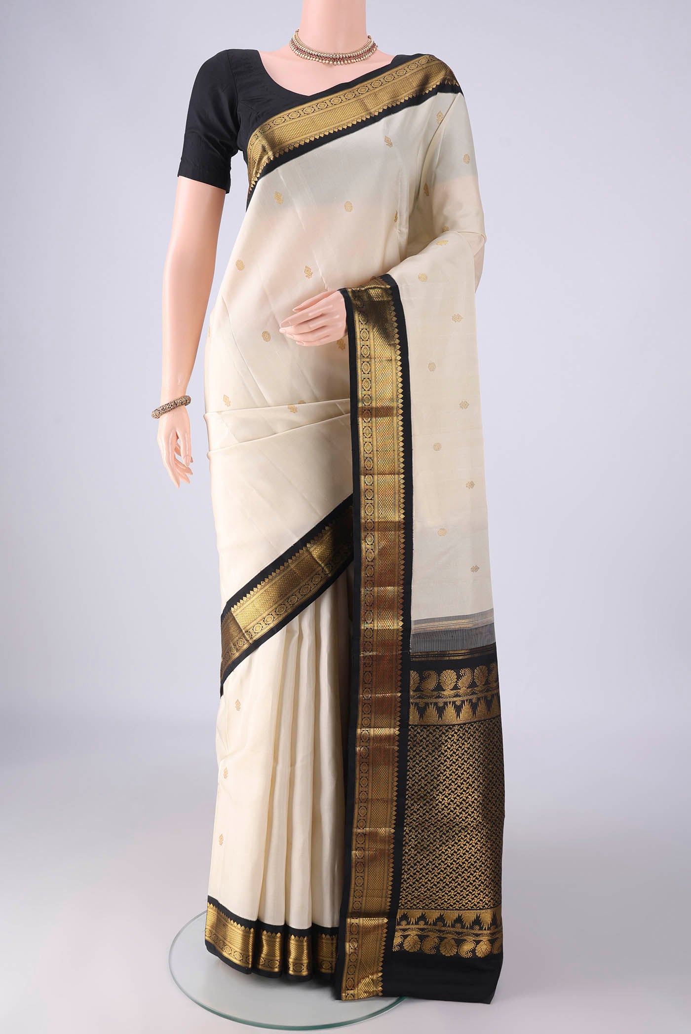 Off White Kanchipuram Silk Saree with Zari Butta on the body and Zari Border.  displayed on a mannequin