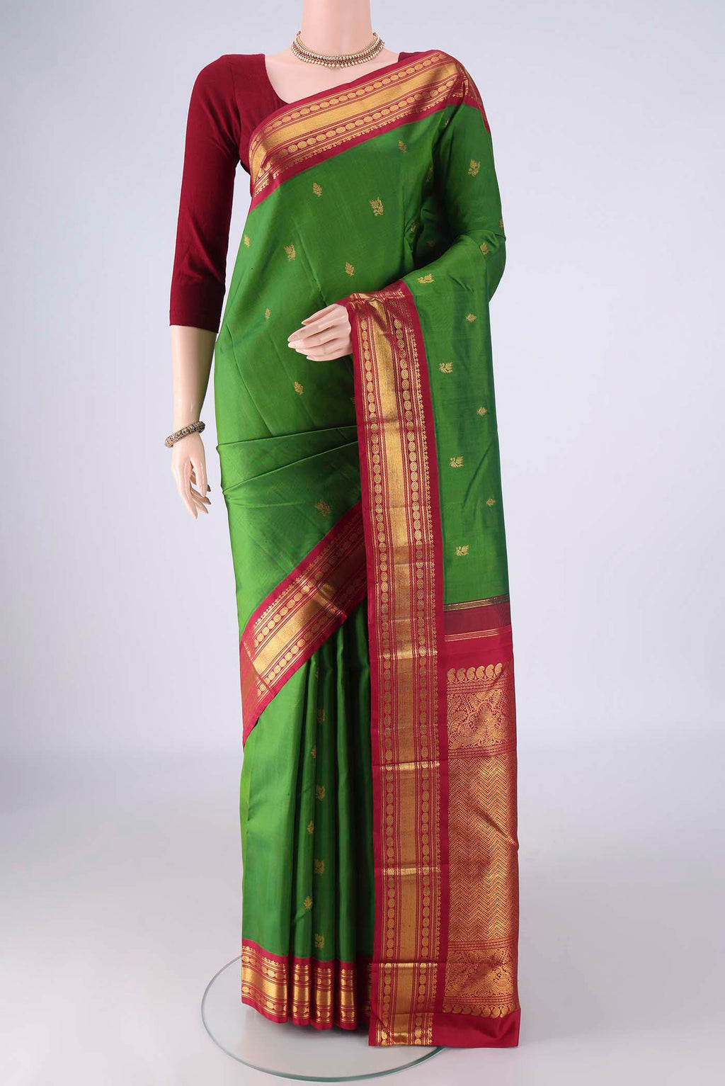 Green Kanchipuram Silk Saree with Zari Butta on the body and Zari Border.  displayed on a mannequin