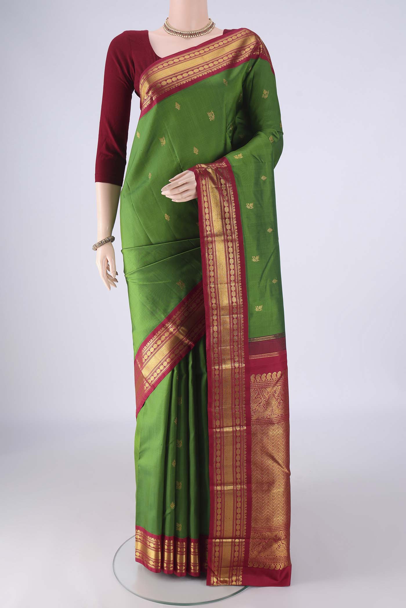 Green Kanchipuram Silk Saree with Zari Butta on the body and Zari Border.  displayed on a mannequin