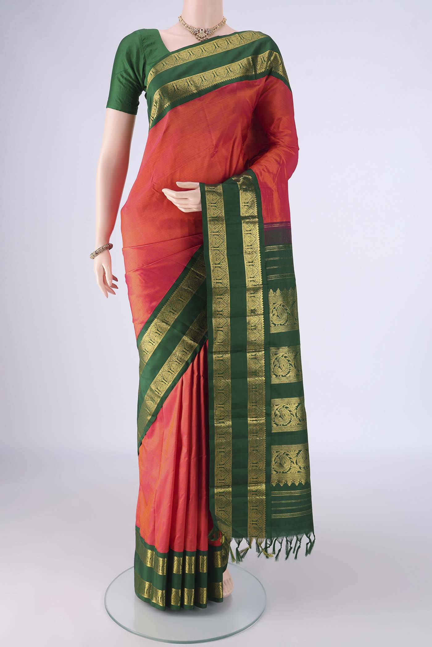 Brick Orange Kanjivaram Silk Saree with Plain Body and Zari Border.  displayed on a mannequin