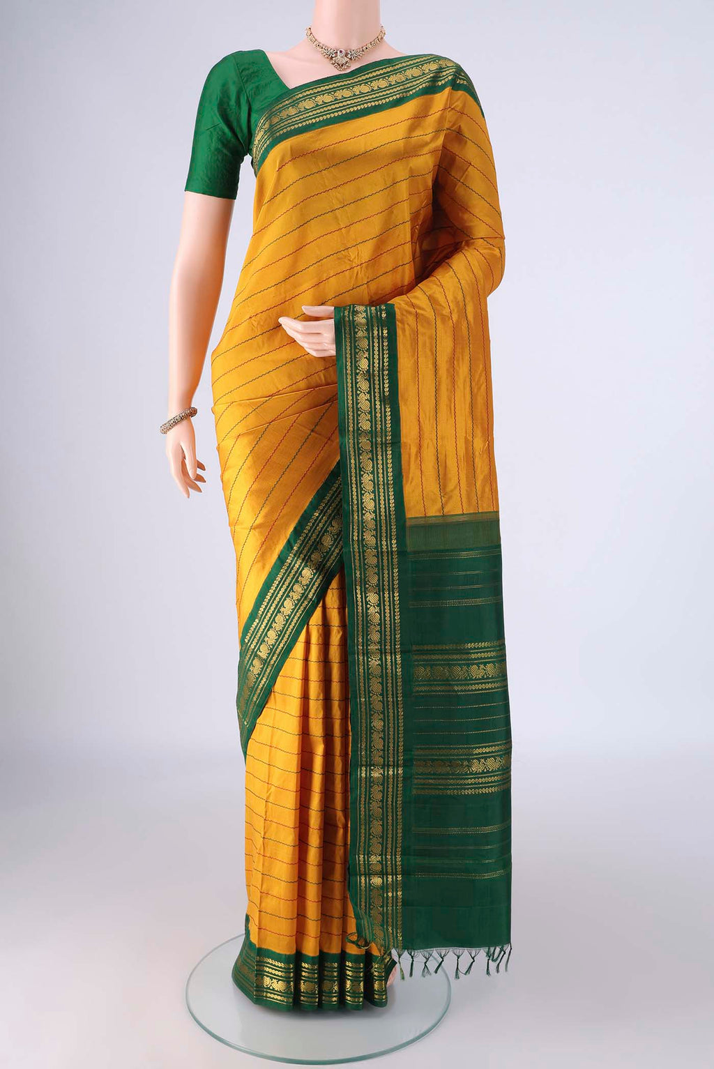 Mustard Kanchipuram Silk Saree with Veldhari on the body and Zari Border.  displayed on a mannequin