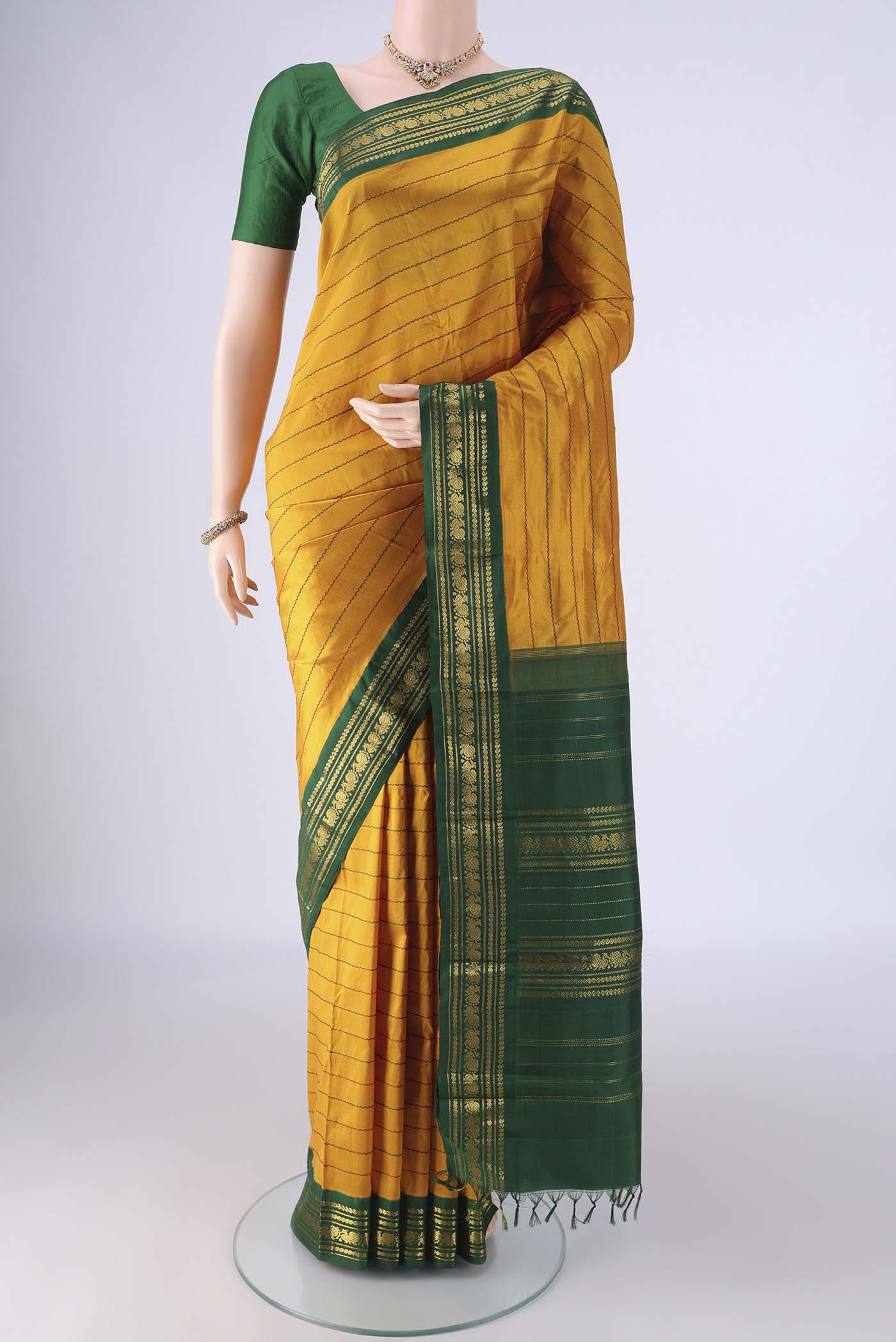 Mustard Kanchipuram Silk Saree with Veldhari on the body and Zari Border.  displayed on a mannequin