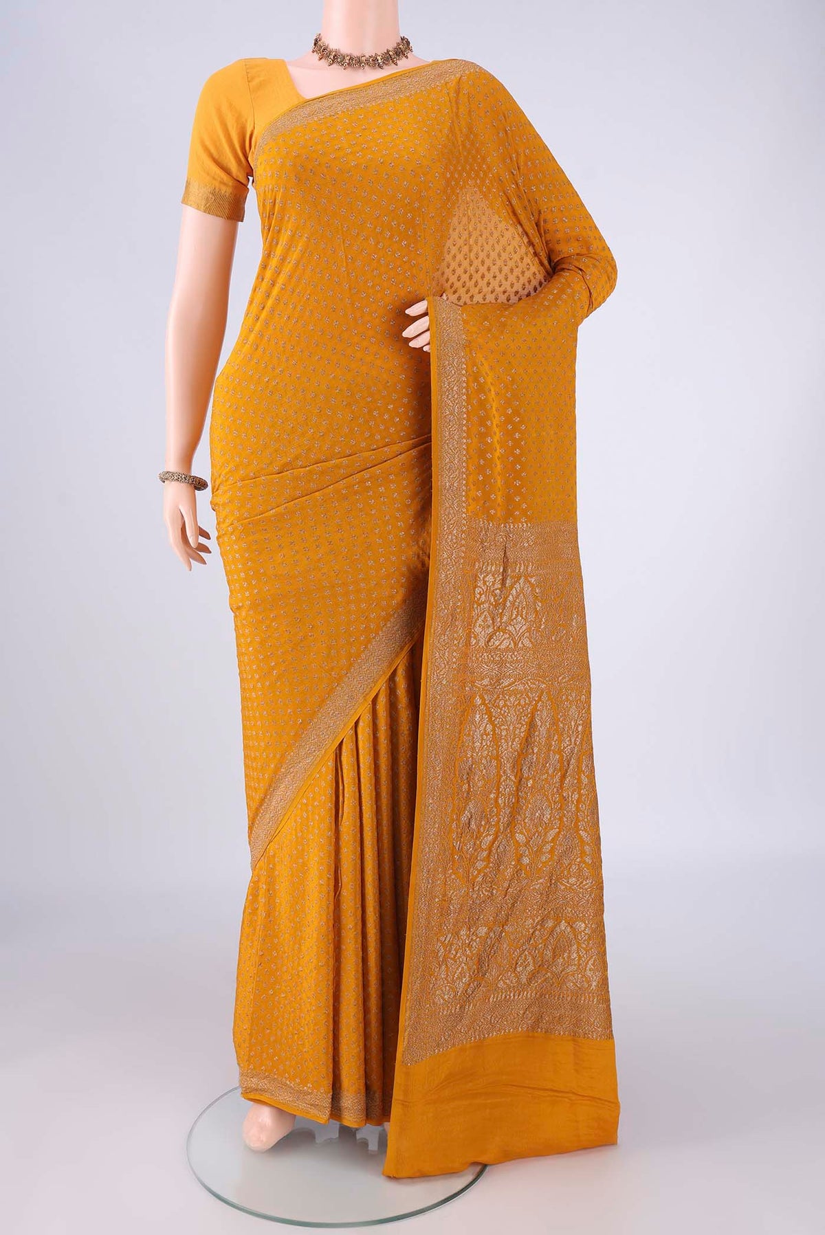 Mustard Banarasi Georgette Saree with Zari Butta on the body and Zari Border.  displayed on a mannequin