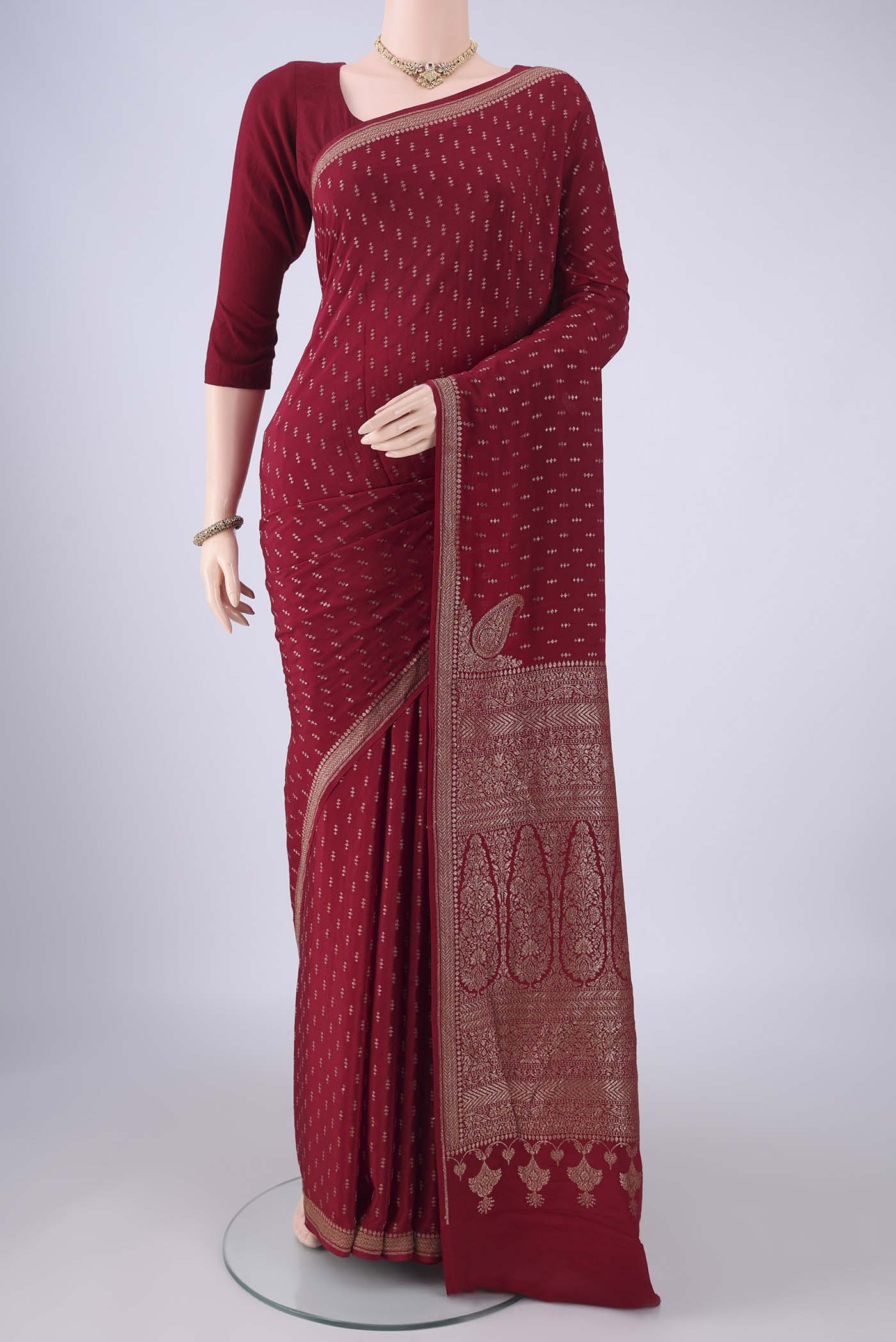 Maroon Banarasi Georgette Saree with Zari Butta on the body and Zari Border.  displayed on a mannequin