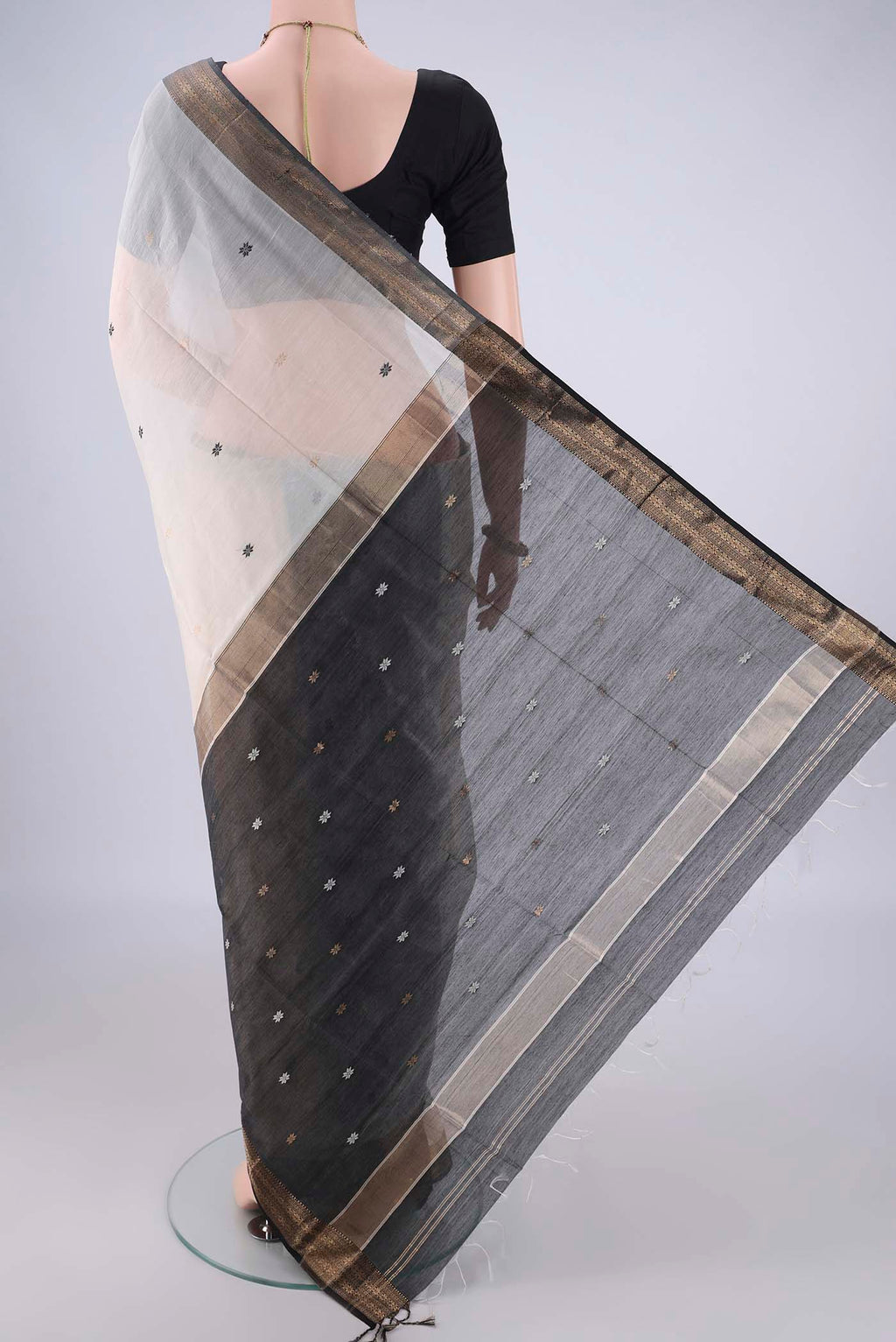 Flat view of White Maheshwari Silk Cotton Saree with Zari And Thread Butta on the body and Zari Border. 