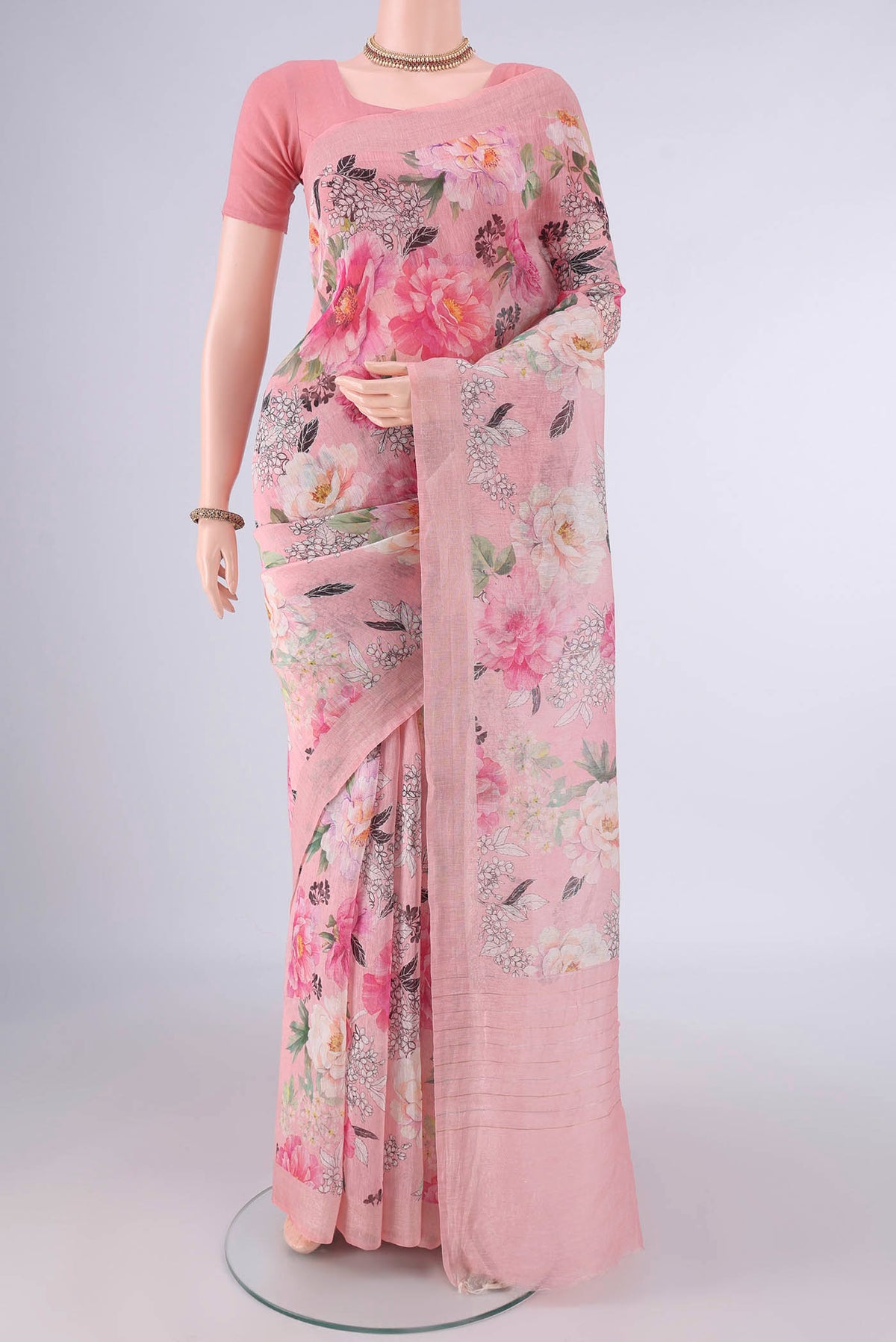 Peach Linen Saree with Floral Print on the body and Zari Border.  displayed on a mannequin
