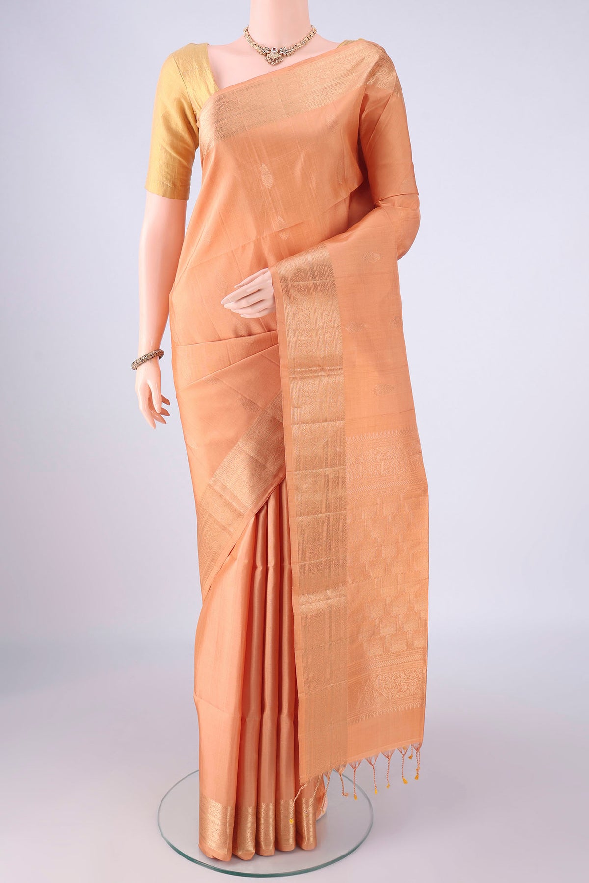 Peach Soft Silk Saree with Zari Butta on the body and Zari Border.  displayed on a mannequin