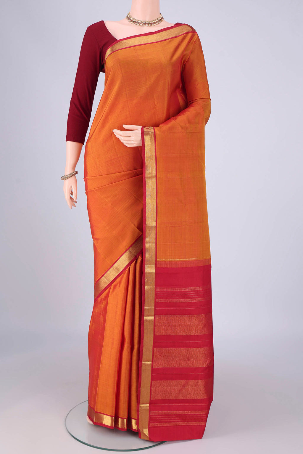 Mustard Kanjivaram Silk Saree with Plain Body and Zari Border.  displayed on a mannequin