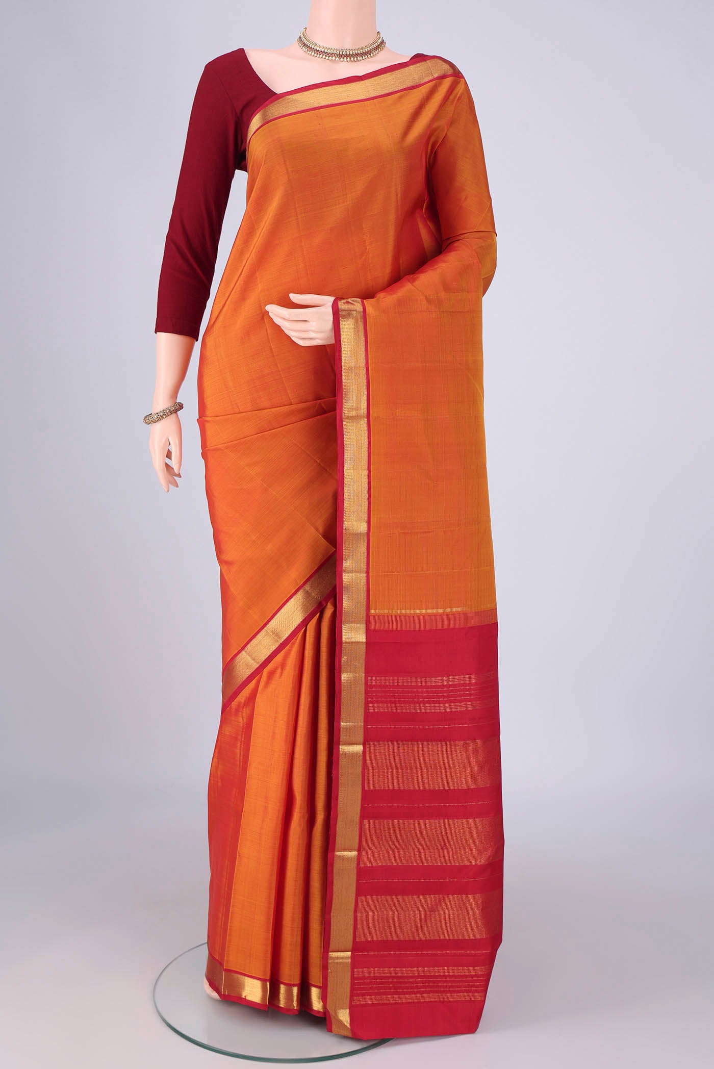 Mustard Kanjivaram Silk Saree with Plain Body and Zari Border.  displayed on a mannequin