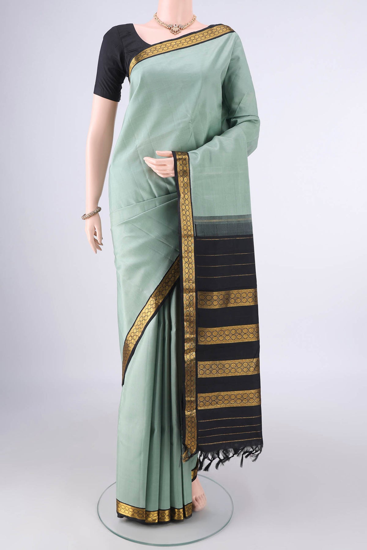 Pure Silk Sage Green Kanjivaram Saree with Plain Body and Zari Border.  displayed on a mannequin