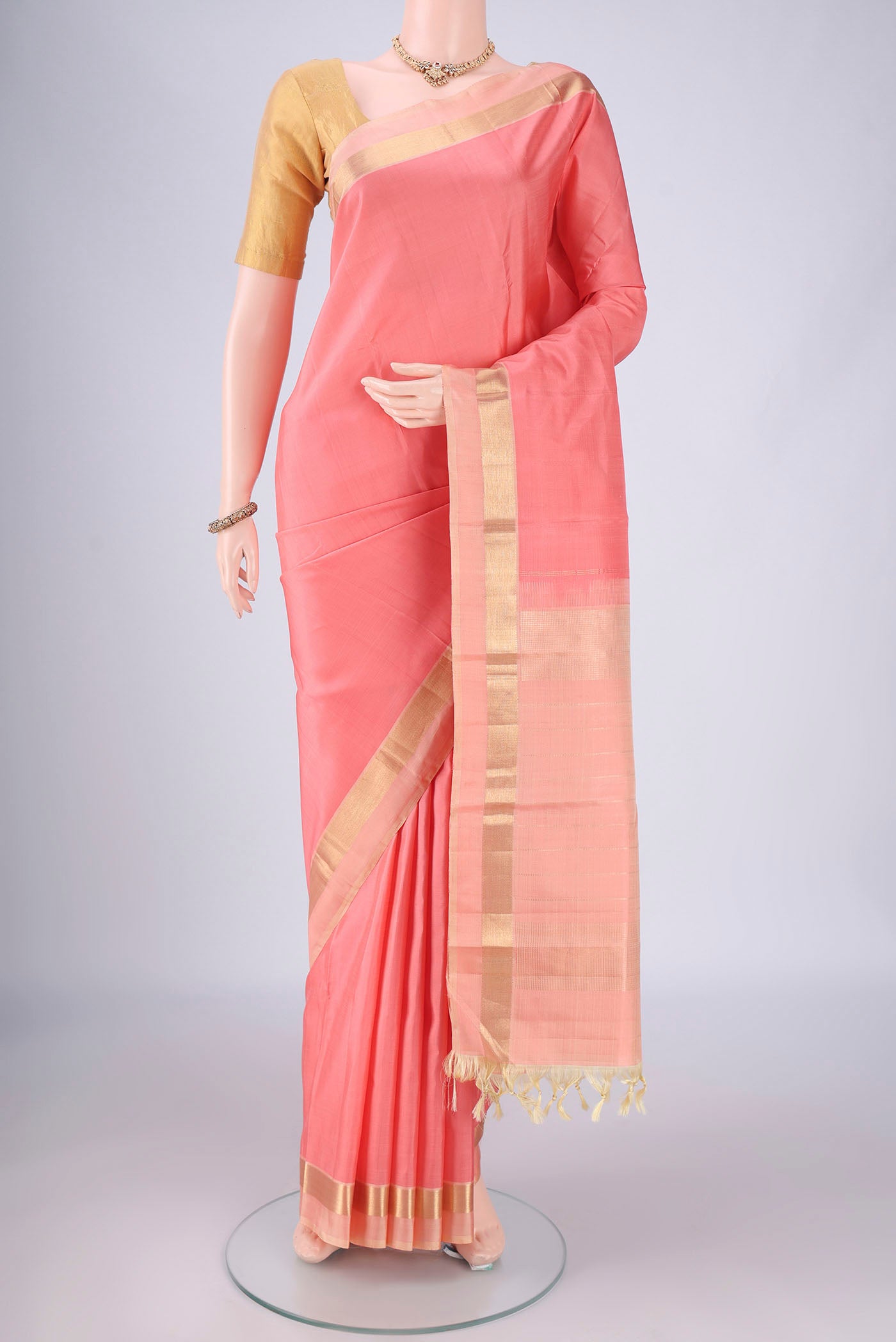Peach Kanchipuram Silk Saree with Plain Body and Zari Border.  displayed on a mannequin