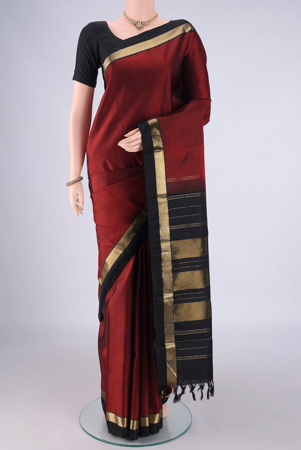 Rust Kanchipuram Silk Saree with Plain Body and Zari Border.  displayed on a mannequin