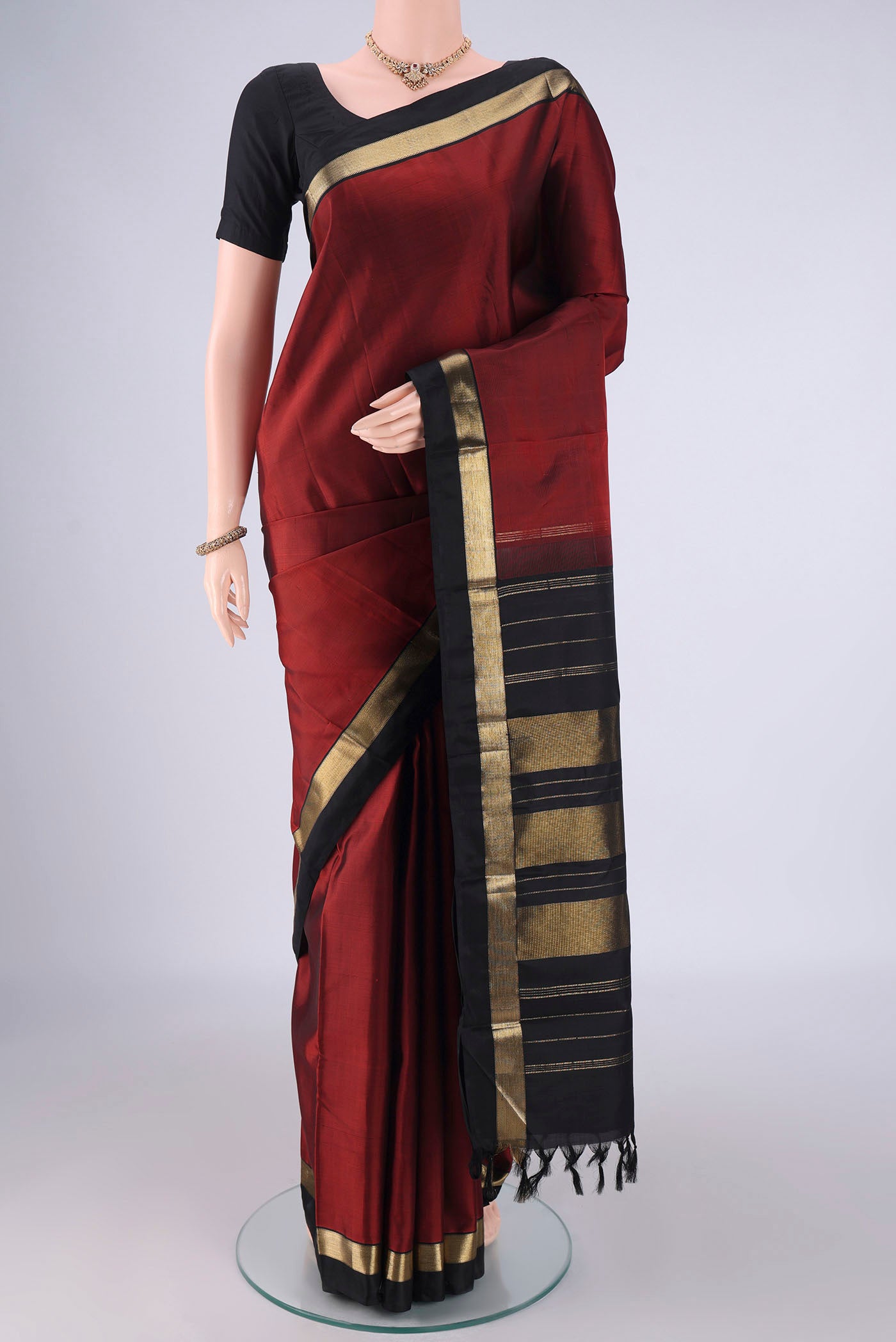 Rust Kanchipuram Silk Saree with Plain Body and Zari Border.  displayed on a mannequin