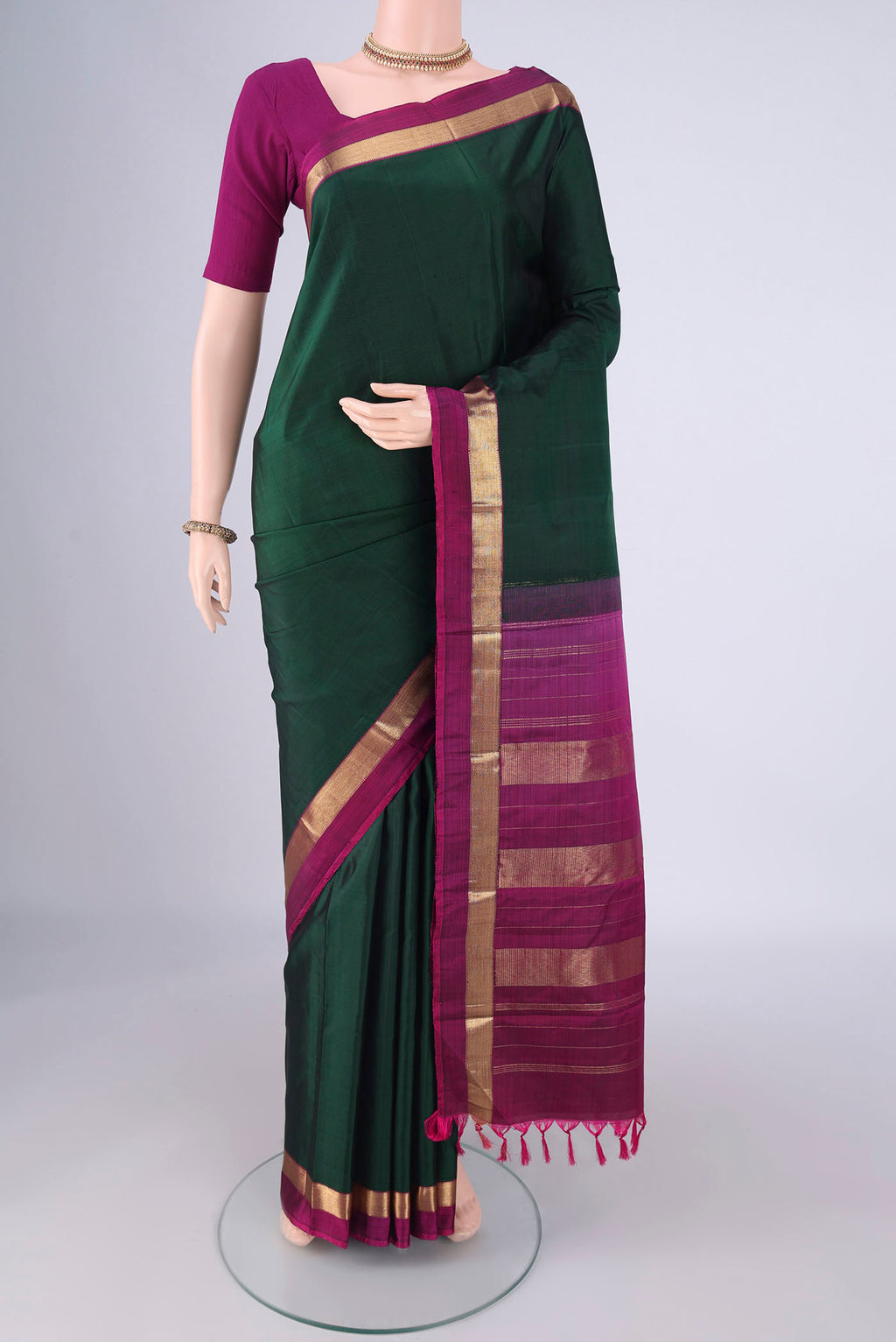 Bottle Green Kanchipuram Silk Saree with Plain Body and Zari Border.  displayed on a mannequin