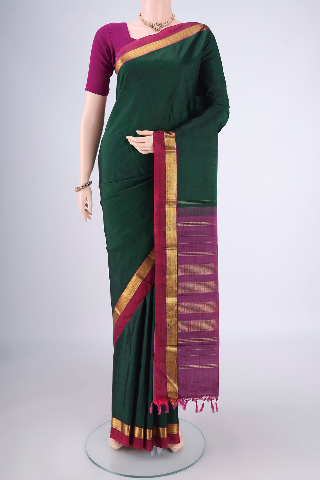 Bottle Green Kanchipuram Silk Saree with Plain Body and Zari Border.  displayed on a mannequin