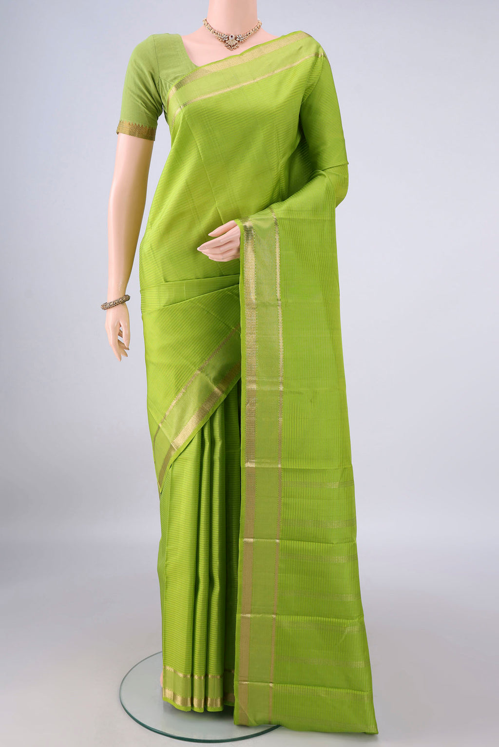 Pure Silk Parrot Green Kanjivaram Saree with Stripes on the body and Zari Border.  displayed on a mannequin