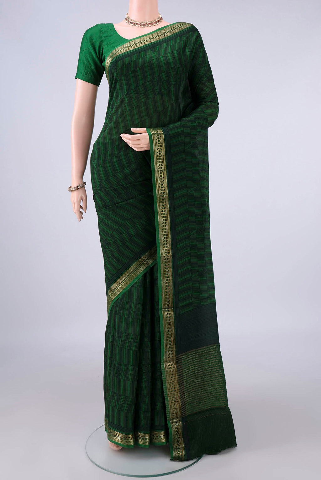 Bottle Green Mysore Crepe Saree with Printed design on the body and Zari Border.  displayed on a mannequin