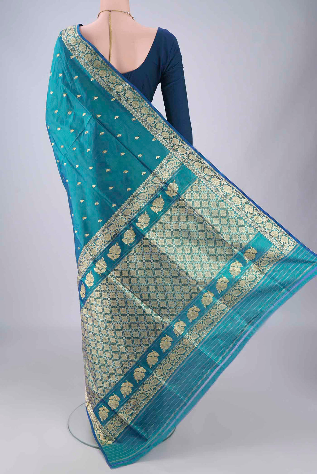 Flat view of Peacock Blue Banarasi Katan Silk Saree with Thread Butta on the body and Thread Border. 