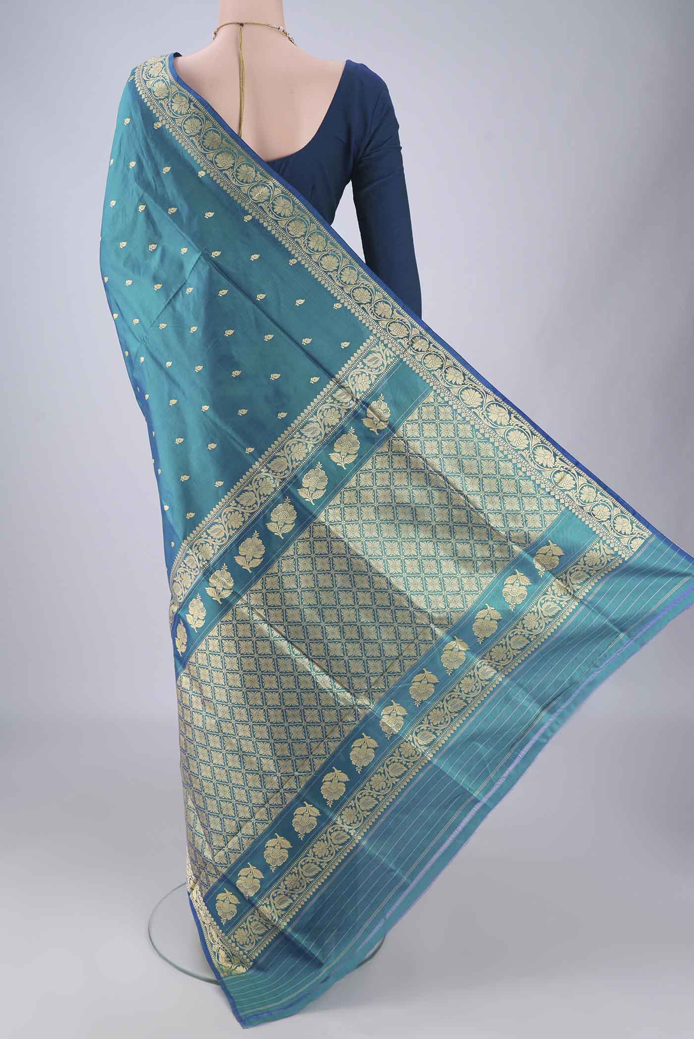 Flat view of Peacock Blue Banarasi Katan Silk Saree with Thread Butta on the body and Thread Border. 