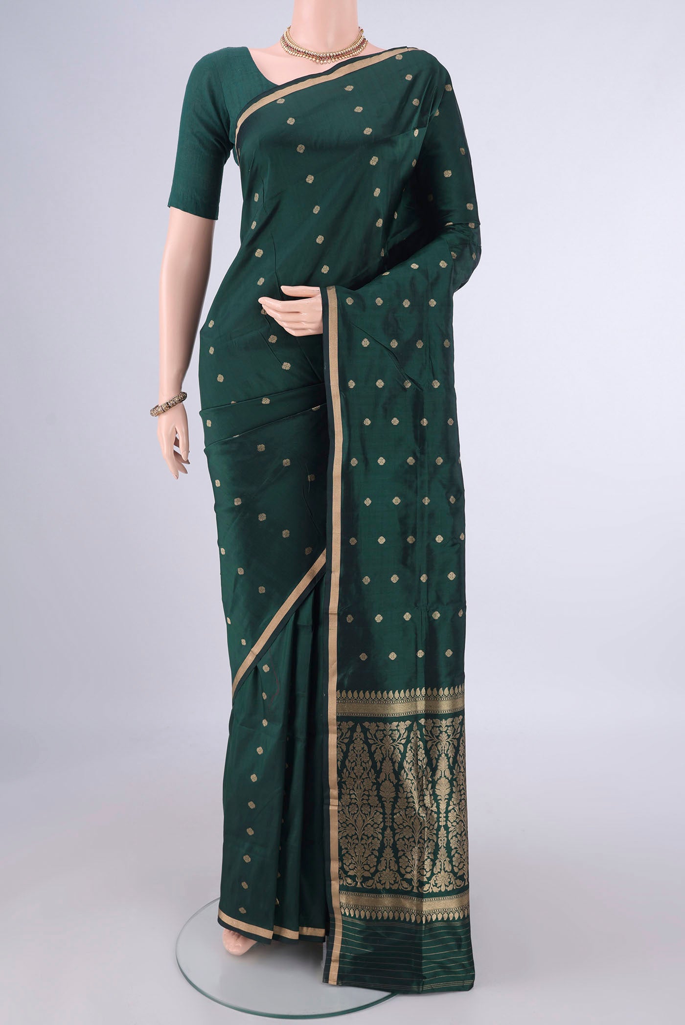 Bottle Green Banarasi Katan Silk Saree with Zari Butta on the body and Zari Border.  displayed on a mannequin