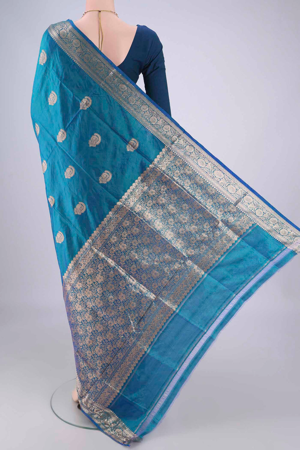 Flat view of Peacock Blue Dual Tone Banarasi Katan Silk Saree with Zari Butta on the body and Zari Border. 