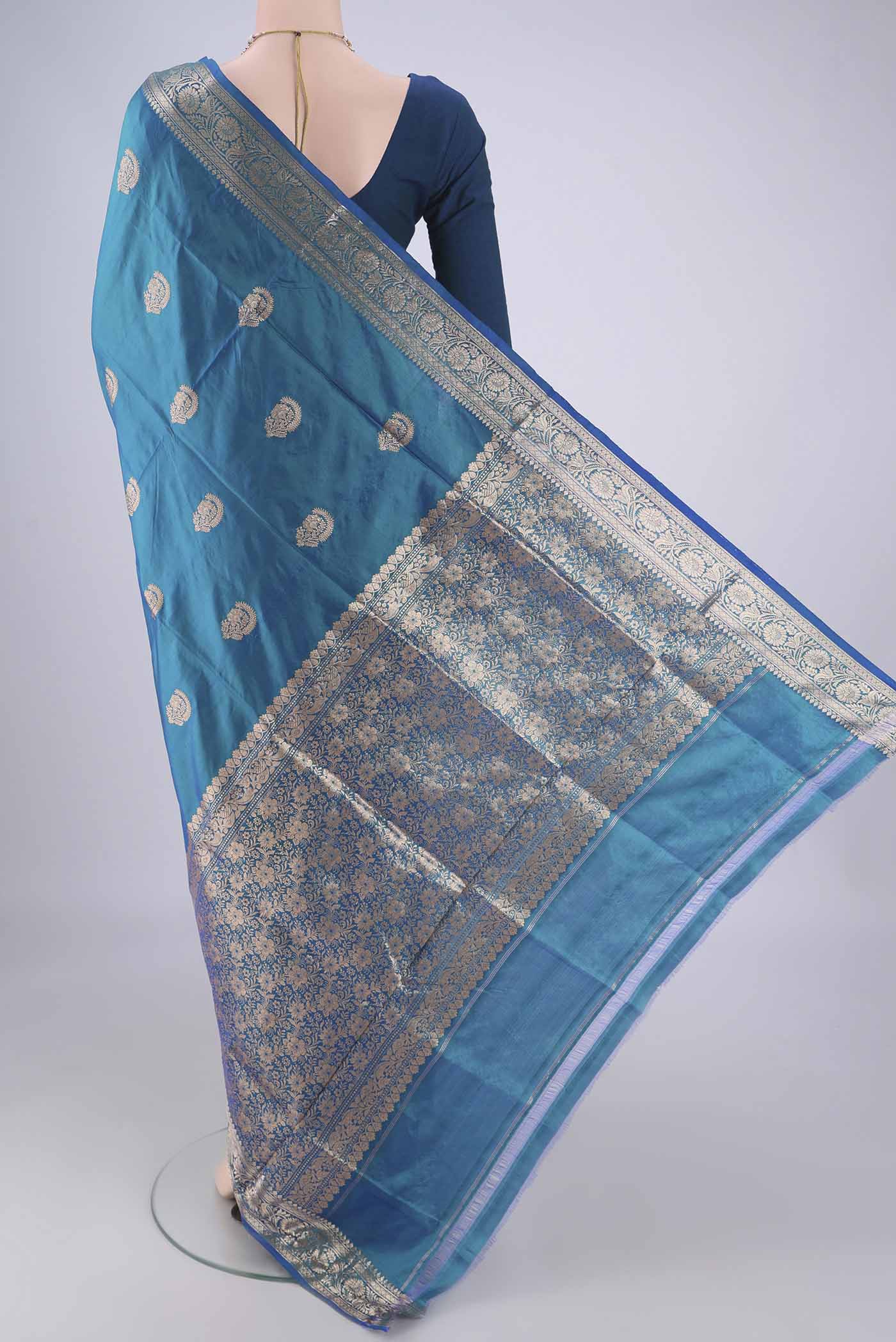 Flat view of Peacock Blue Dual Tone Banarasi Katan Silk Saree with Zari Butta on the body and Zari Border. 