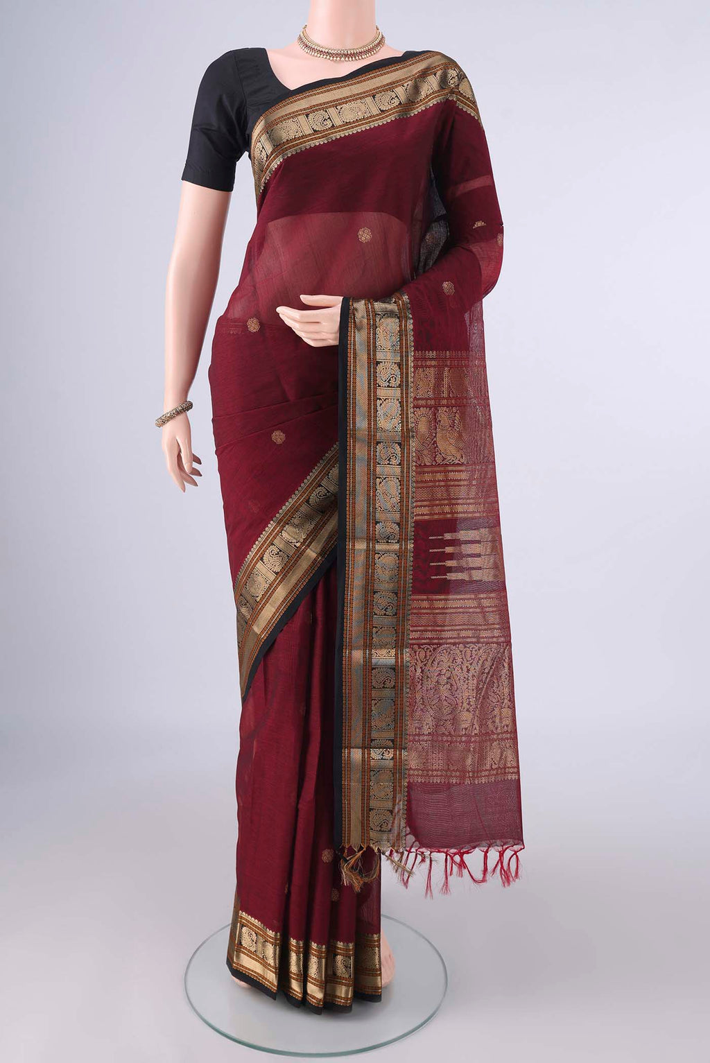Maroon Kanchi Cotton Saree with Zari Butta on the body and Zari Border.  displayed on a mannequin