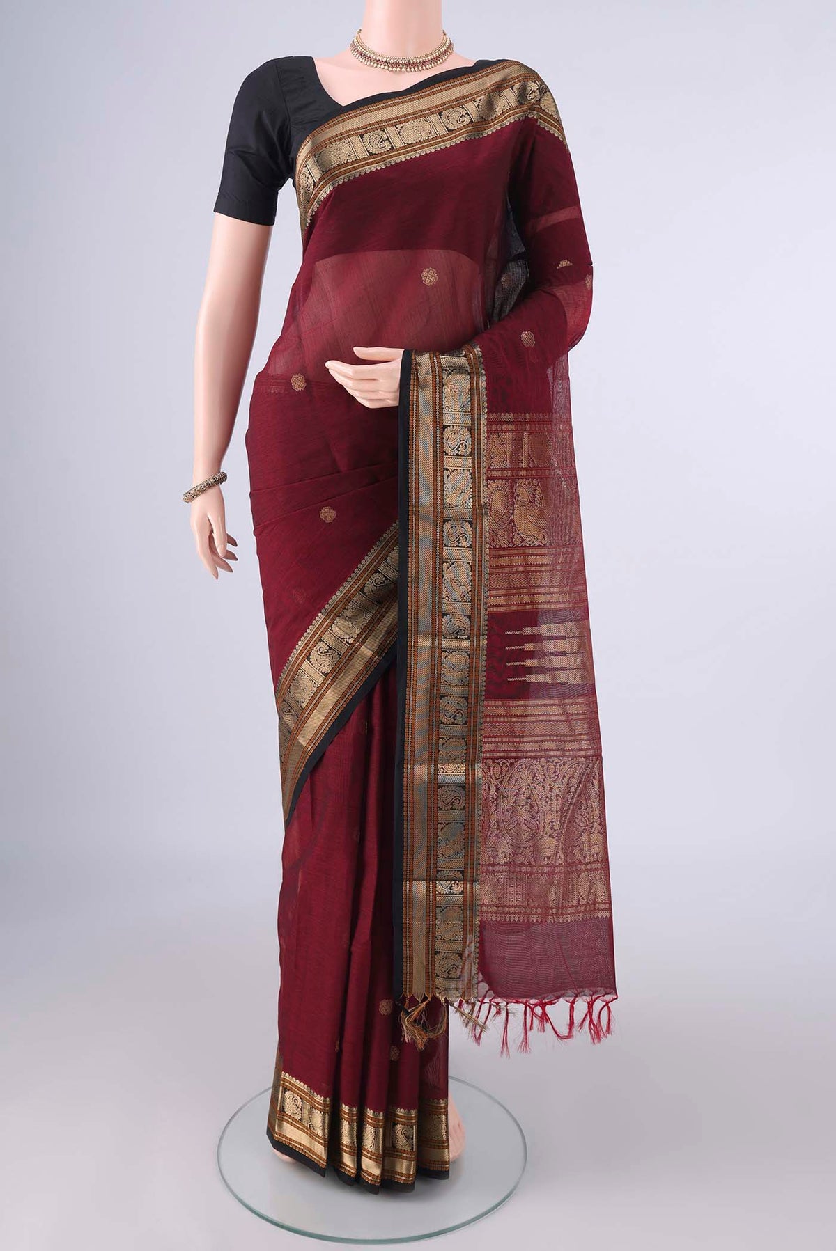 Maroon Kanchi Cotton Saree with Zari Butta on the body and Zari Border.  displayed on a mannequin