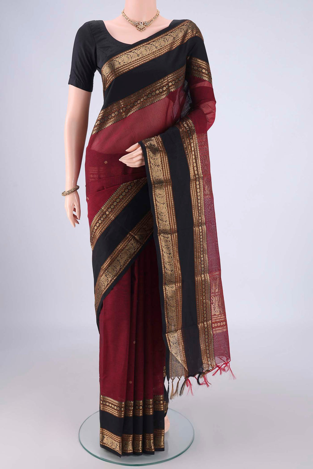 Maroon Kanchi Cotton Saree with Zari Butta on the body and Zari Border.  displayed on a mannequin